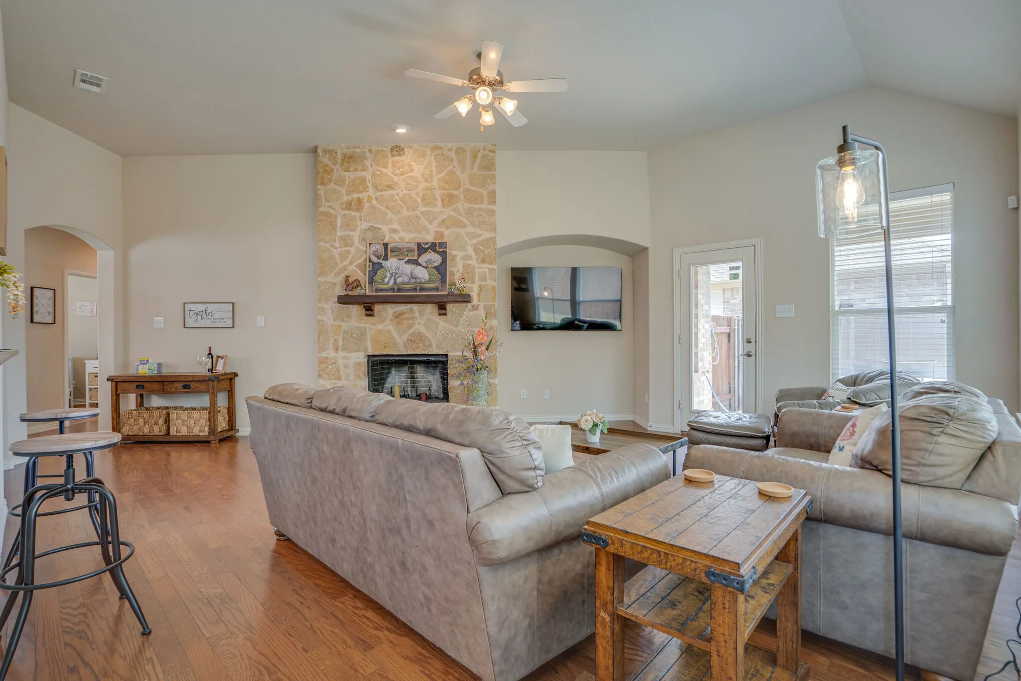 Vaulted ceilings and wood-finish flooring complement a floor-to-ceiling stone-faced fireplace with a wood mantel