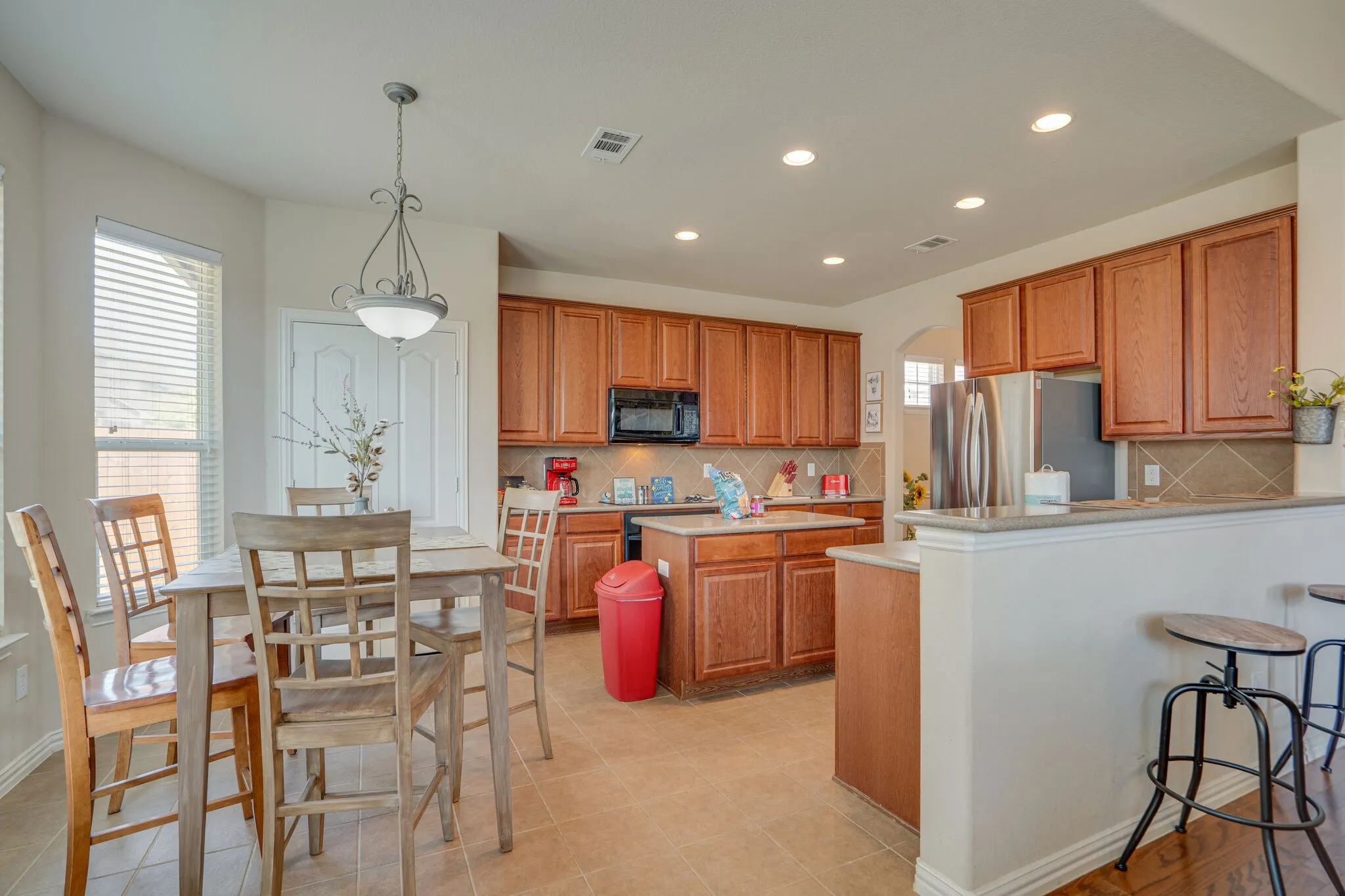 Kitchen featuring wood-finish cabinetry, stainless steel refrigerator, built-in microwave, tile flooring, and recessed lighting