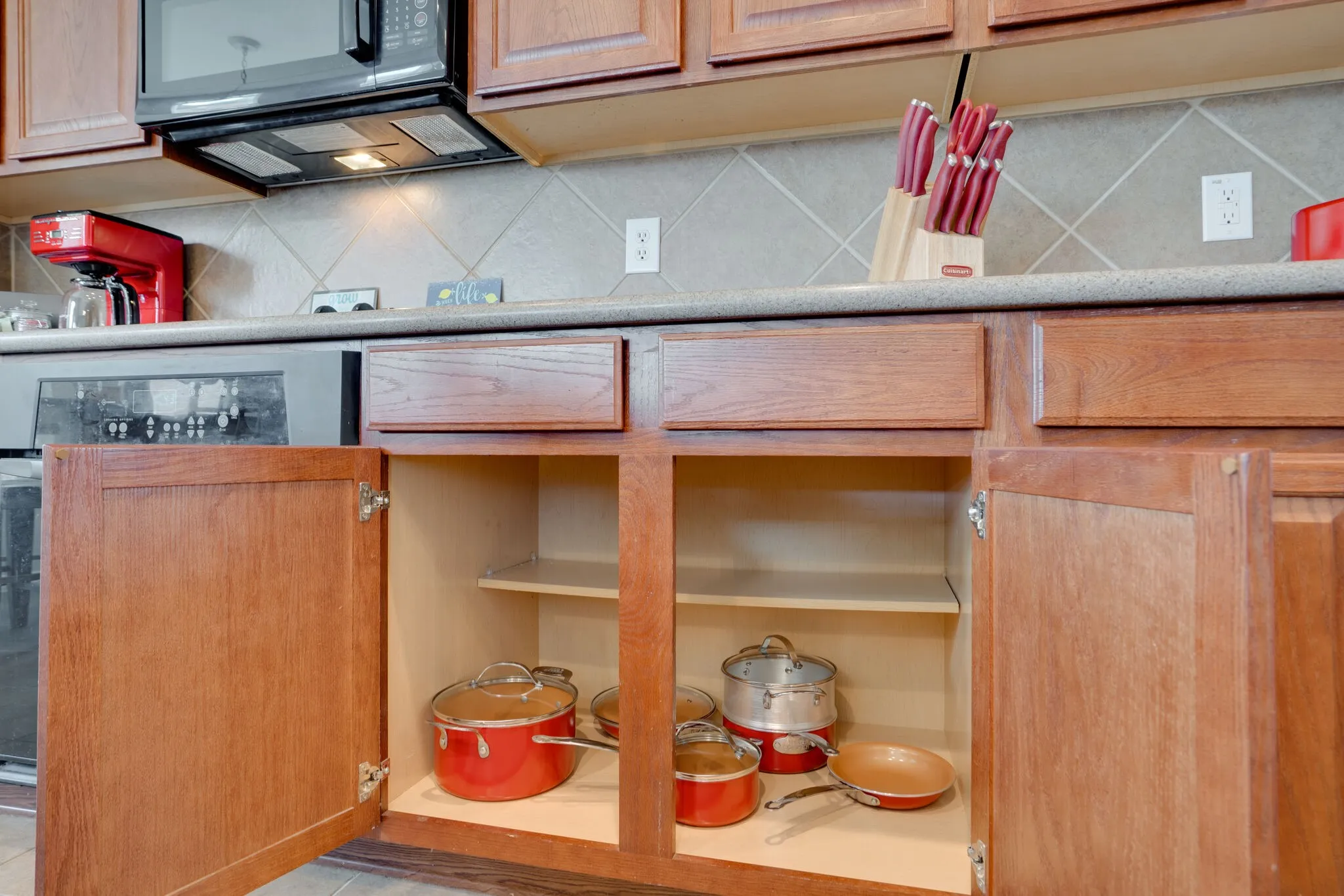 Warm wood-finish cabinetry with visible grain, light-toned countertops, and a neutral diamond-patterned tile backsplash