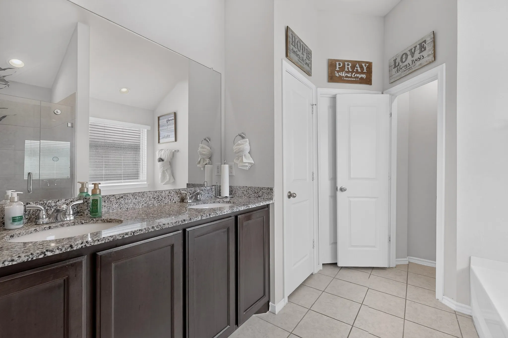 Double vanity with granite-style countertop, dual undermount sinks, chrome fixtures, and dark wood-finish cabinetry