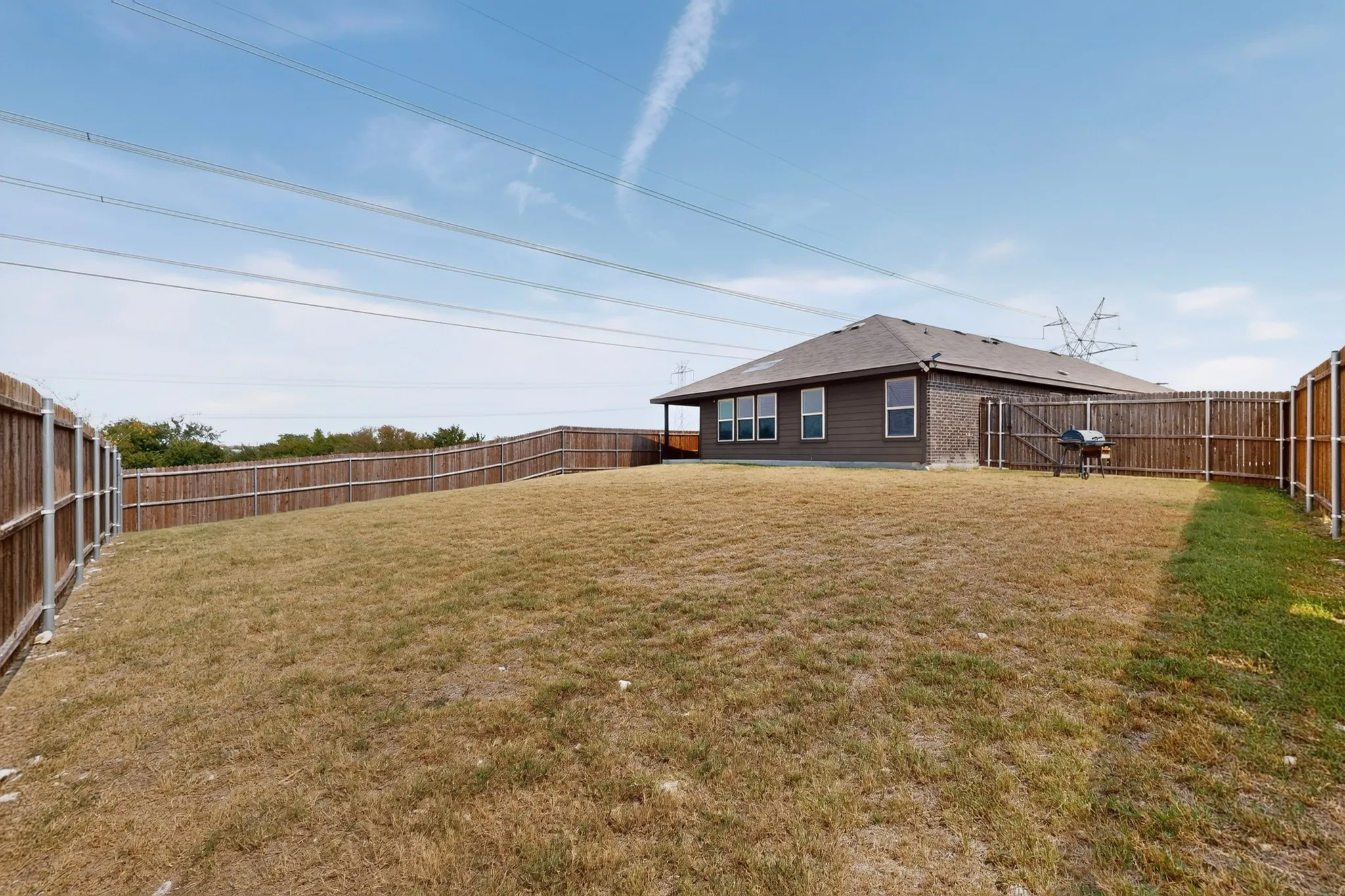 Expansive backyard featuring wood privacy fencing, a manicured lawn, and a back patio