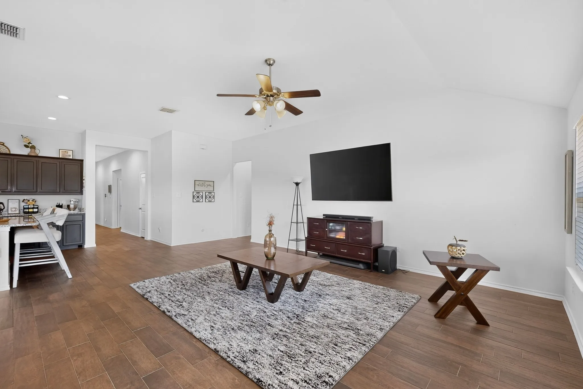 Vaulted ceiling with a ceiling fan, recessed lighting, wood-finish flooring, and dark cabinetry