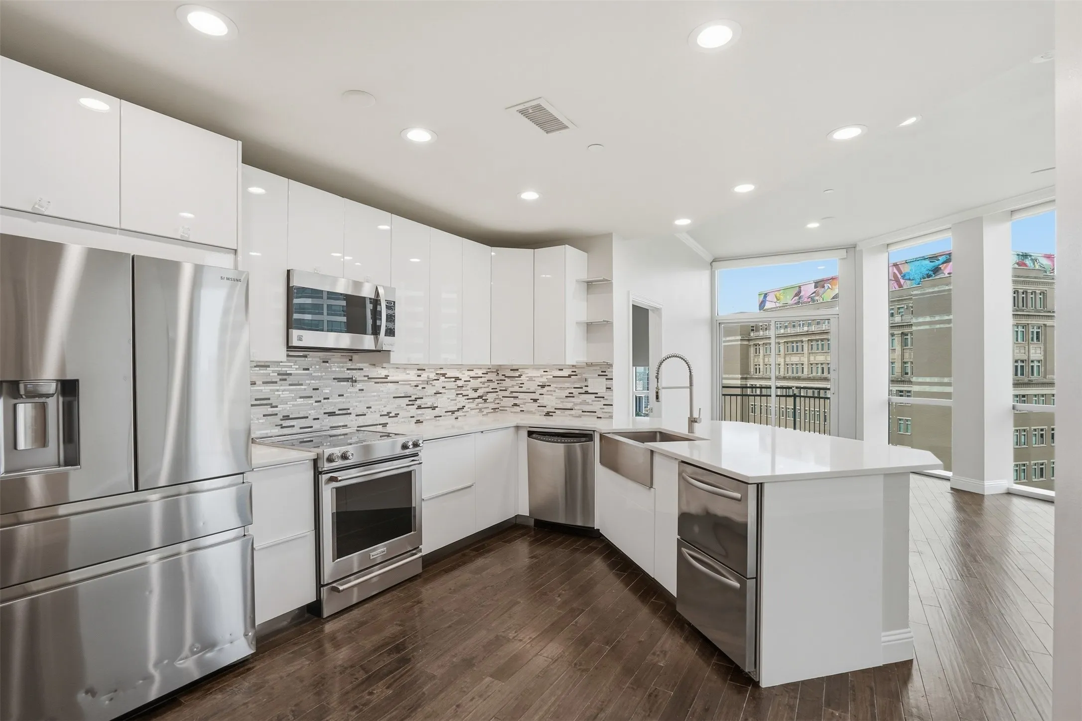 Sleek kitchen featuring white cabinetry, stainless steel appliances, a farmhouse sink, stone countertops, and wood-finish flooring