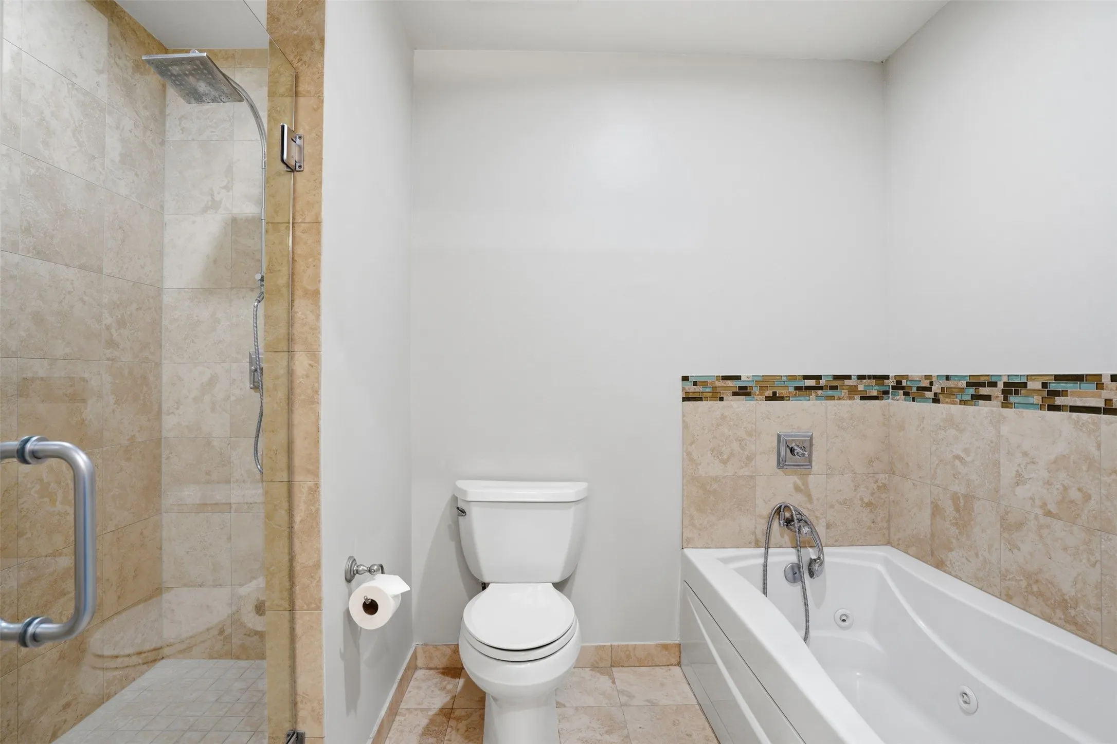 Tiled shower enclosure with a rainfall shower head, glass shower door, and a built-in tub with jets