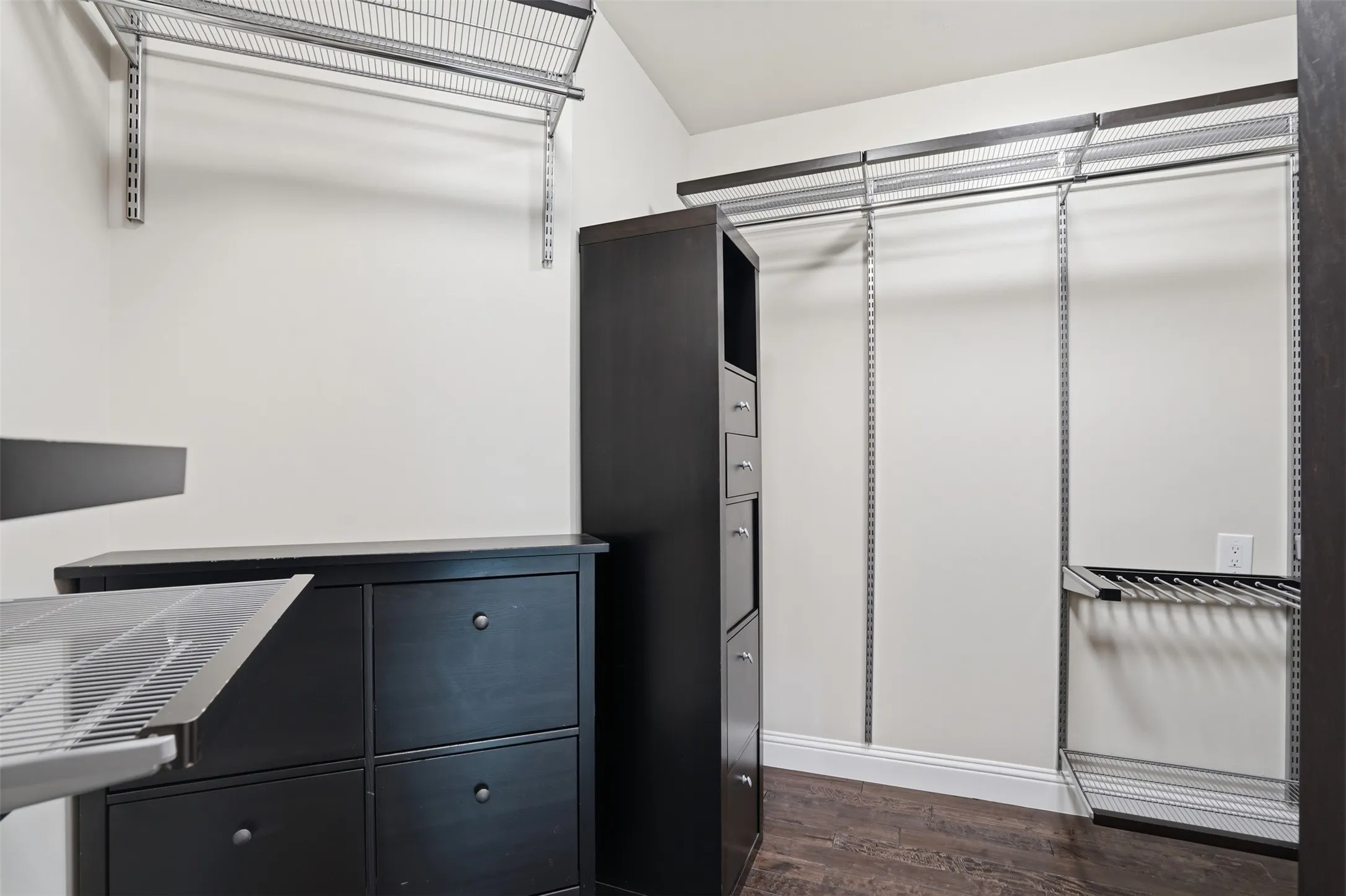 Built-in shelving and hanging rods, dark wood-finish flooring, and white baseboards