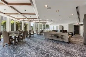 Spacious common area featuring full-height windows, coffered ceilings with recessed lighting, and patterned carpeting