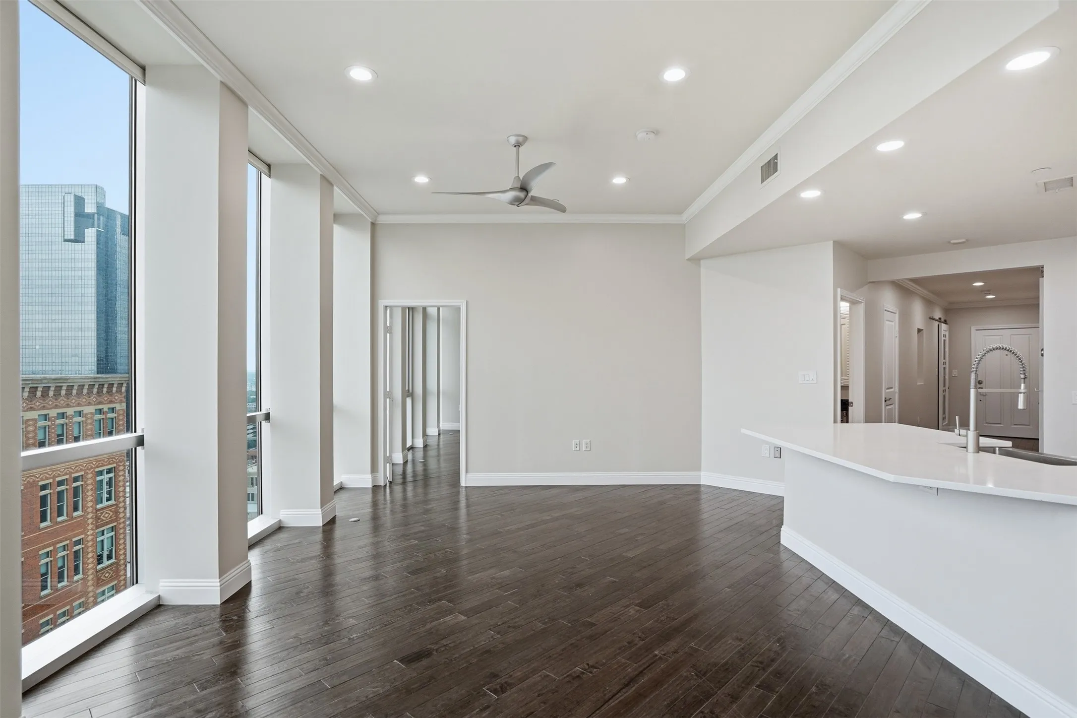 Expansive living area featuring large windows, dark wood-finish flooring, recessed lighting, and a ceiling fan