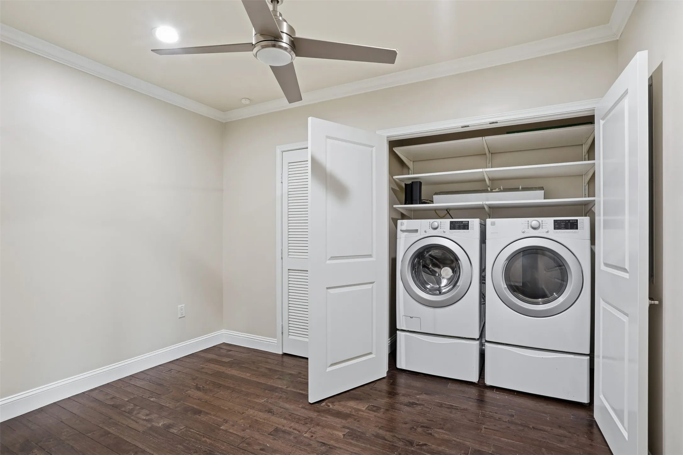 Wood-finish flooring, ceiling fan, crown molding, recessed lighting, and a laundry closet with shelving