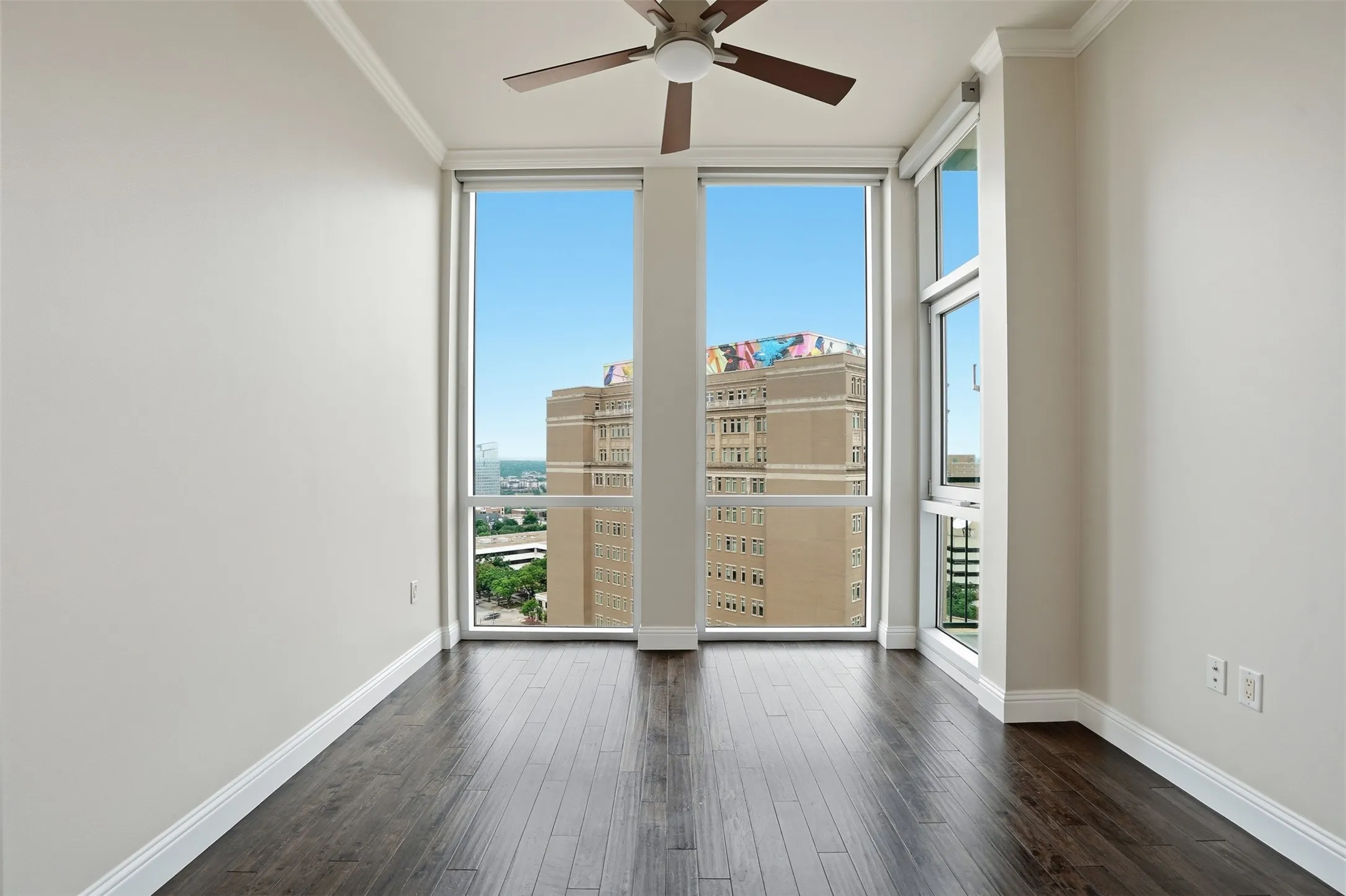 Expansive windows providing abundant natural light, crown molding, wood-finish flooring, and a ceiling fan