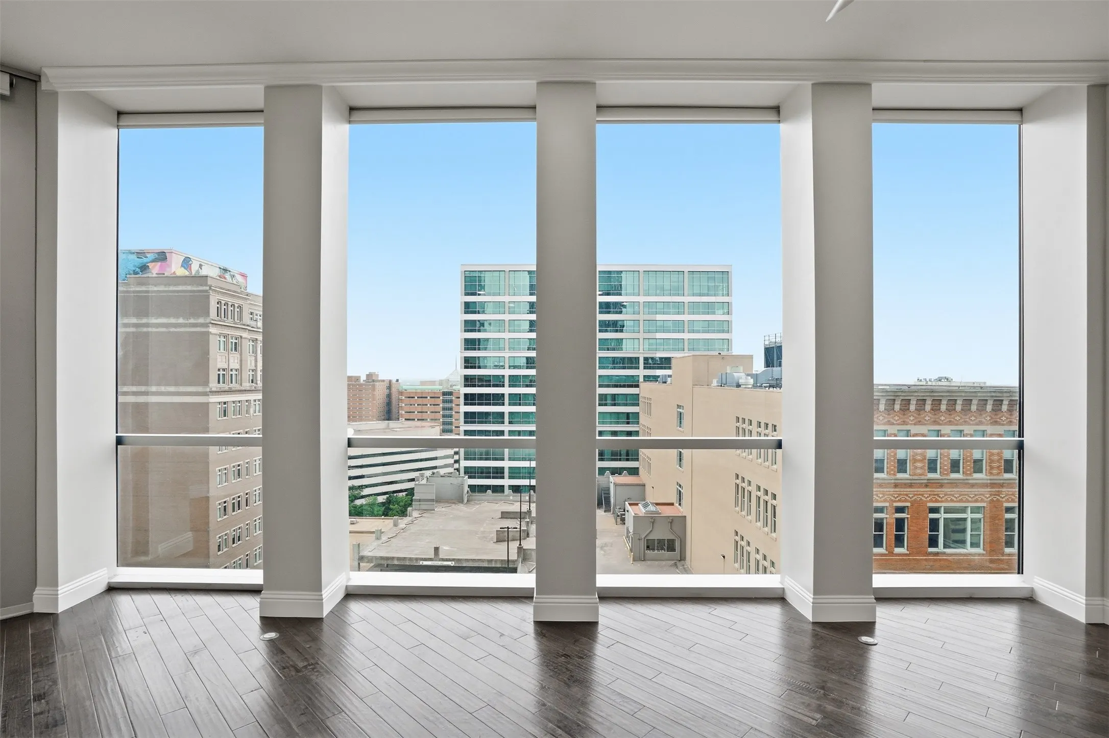 Expansive window wall with multiple panels, dark wood-finish flooring, and white trim