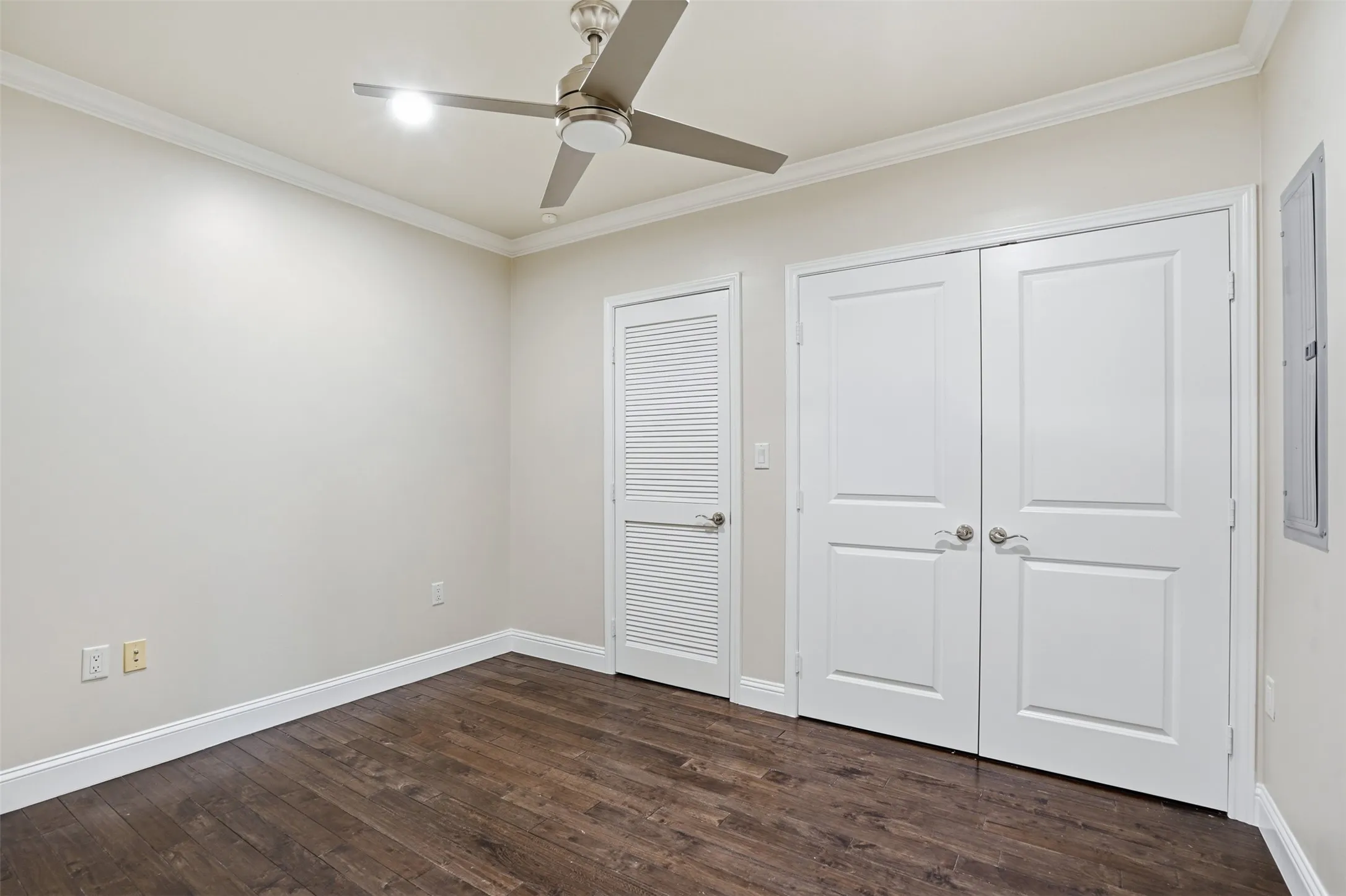 Wood-finish flooring, crown molding, and a ceiling fan