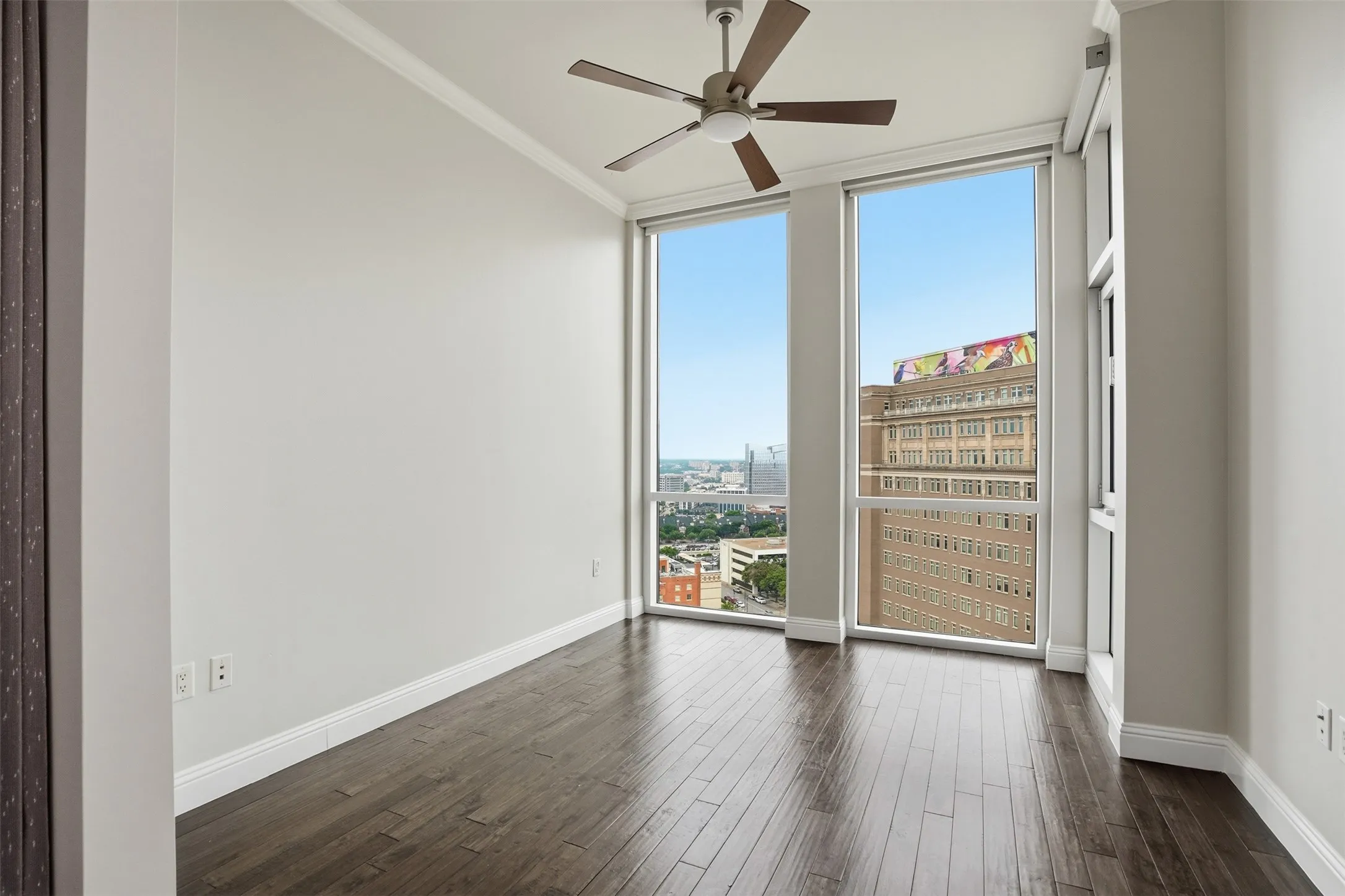 Dark wood-finish flooring with floor-to-ceiling windows, a ceiling fan, and white crown molding