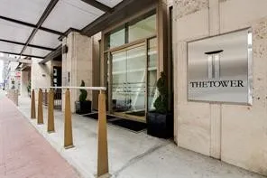 The Tower Entrance entrance featuring a metal awning, glass entry doors, and a stone facade