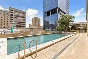 Outdoor swimming pool with concrete decking, surrounding urban architecture, and established landscaping