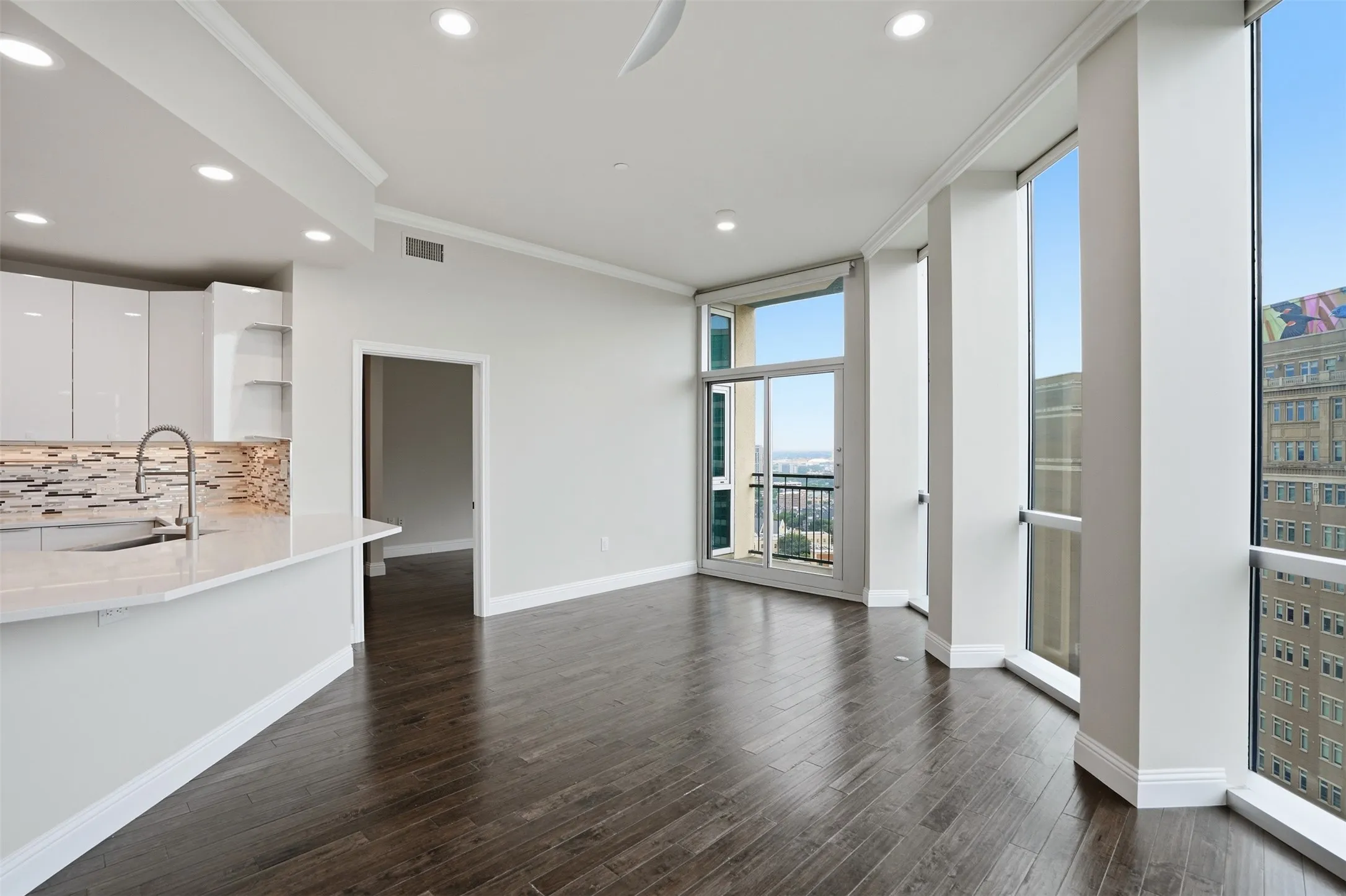 Open-concept living space with dark wood-finish flooring, recessed lighting, and expansive floor-to-ceiling windows