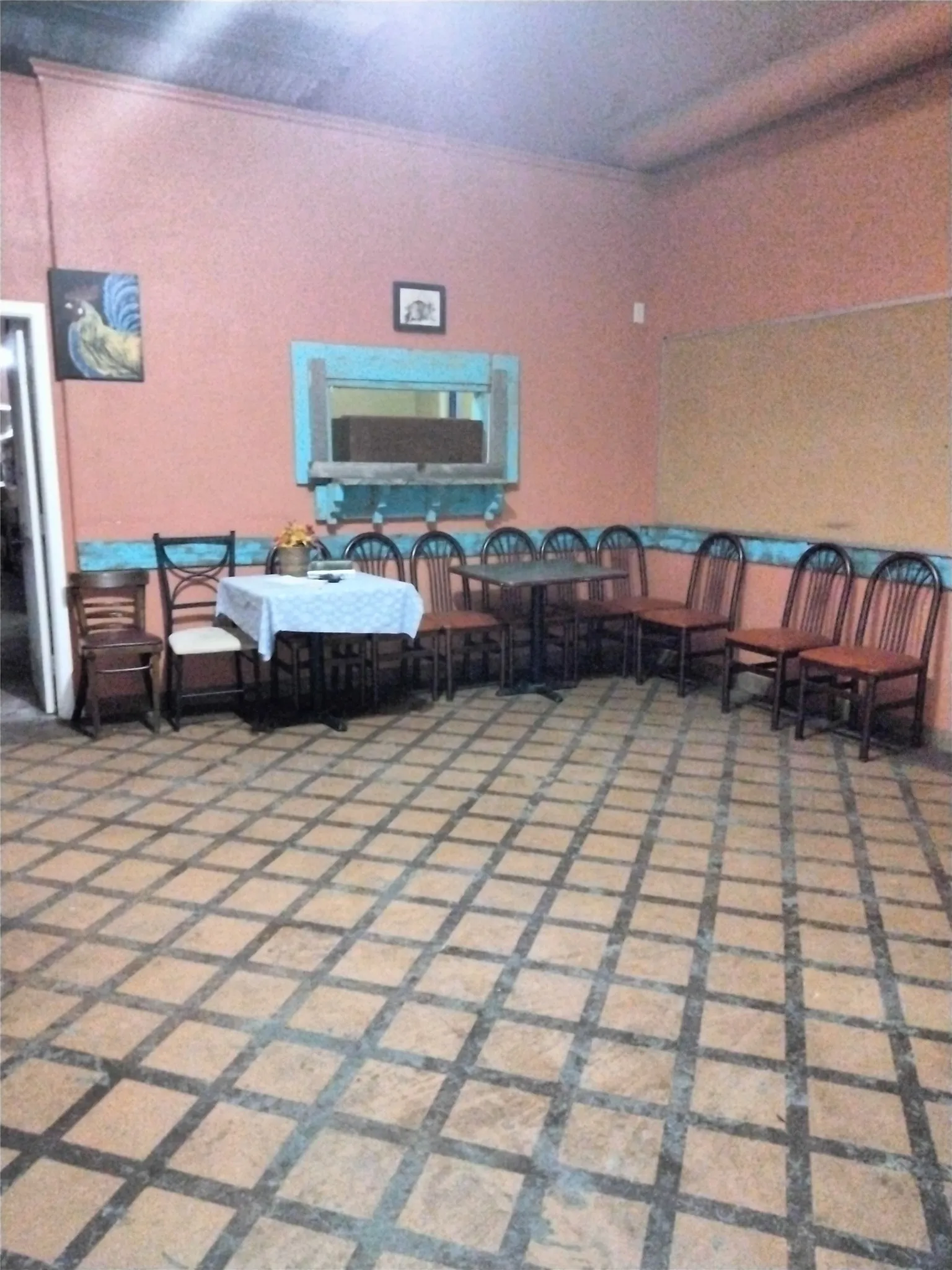 Expansive room featuring a checkerboard-patterned floor, a high ceiling, and a built-in shelf with a mirror
