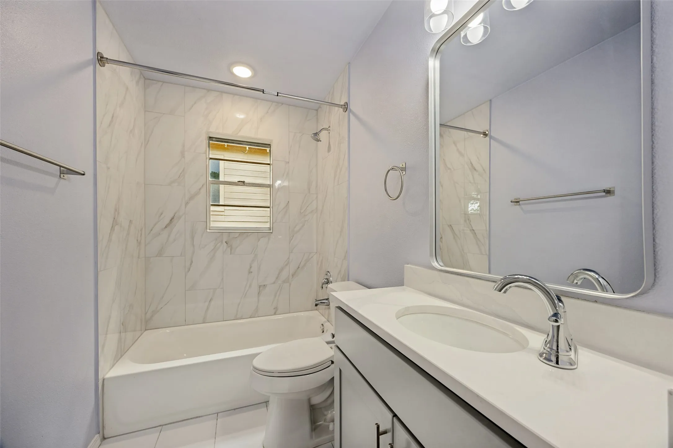 Bathtub with white tile surround, single-sink vanity with white countertop, chrome faucet, and rectangular mirror
