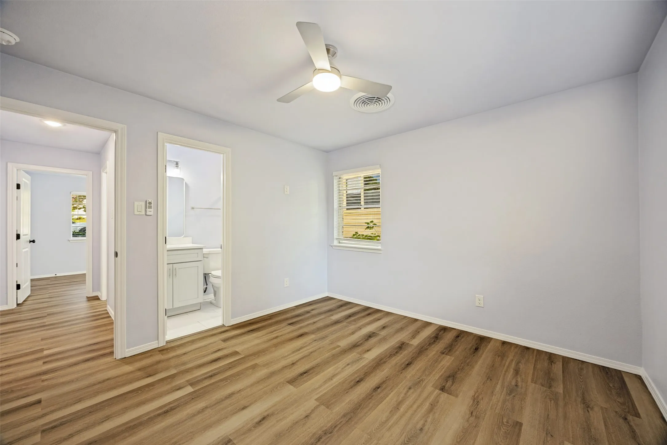 Interior room featuring wood-finish flooring, a ceiling fan with integrated lighting, and a window with horizontal blinds
