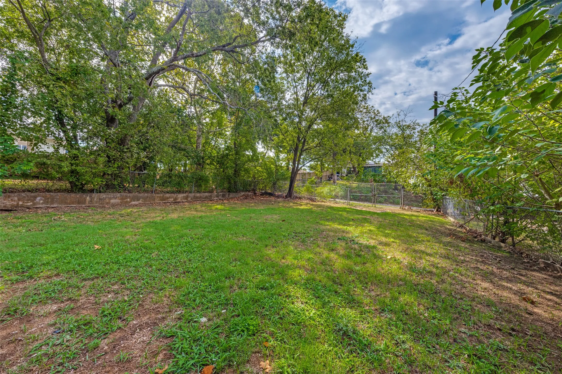 Expansive lawn area with mature trees and perimeter fencing