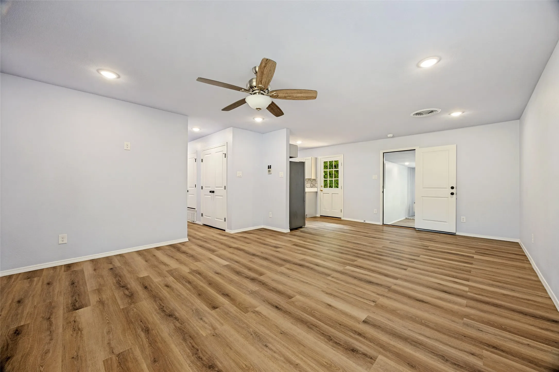 Spacious living area featuring wood-finish flooring, recessed lighting, and a ceiling fan