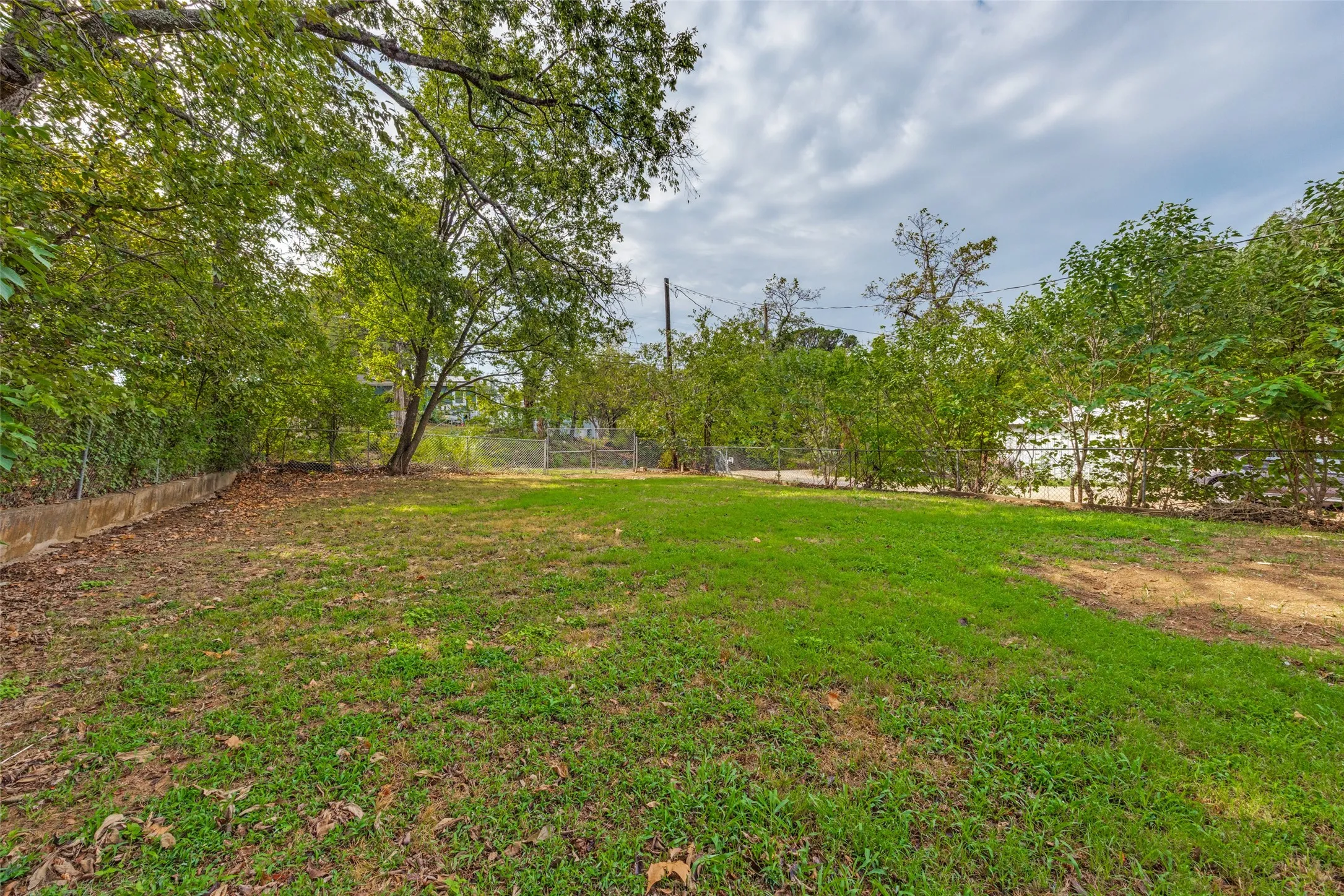 Expansive green lawn with mature trees and perimeter fencing