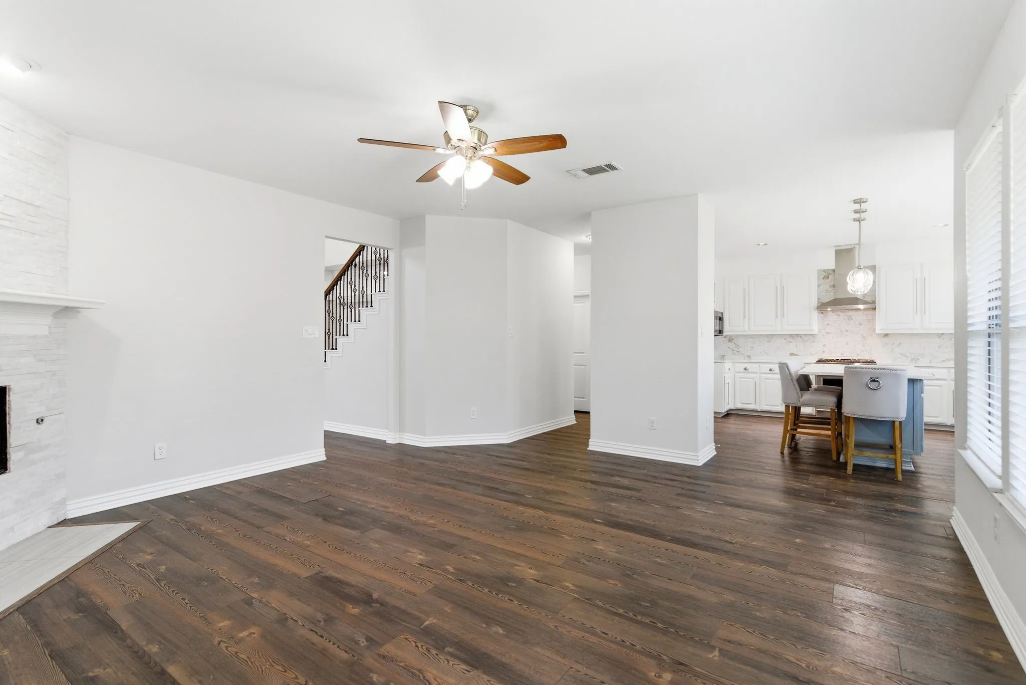 Wood-finish flooring, ceiling fan, white paneled cabinets, kitchen island, and stainless steel appliances