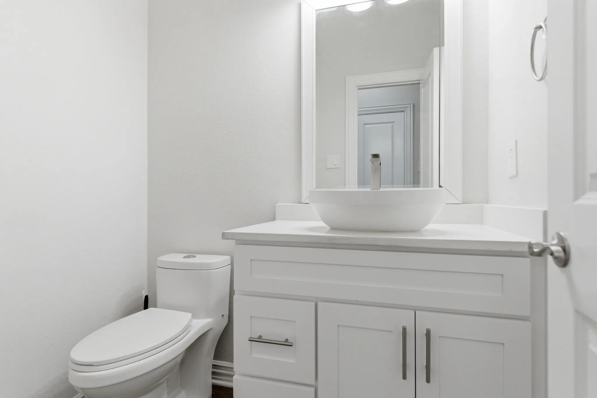 White vanity with shaker-style cabinetry, a white countertop, and a vessel sink