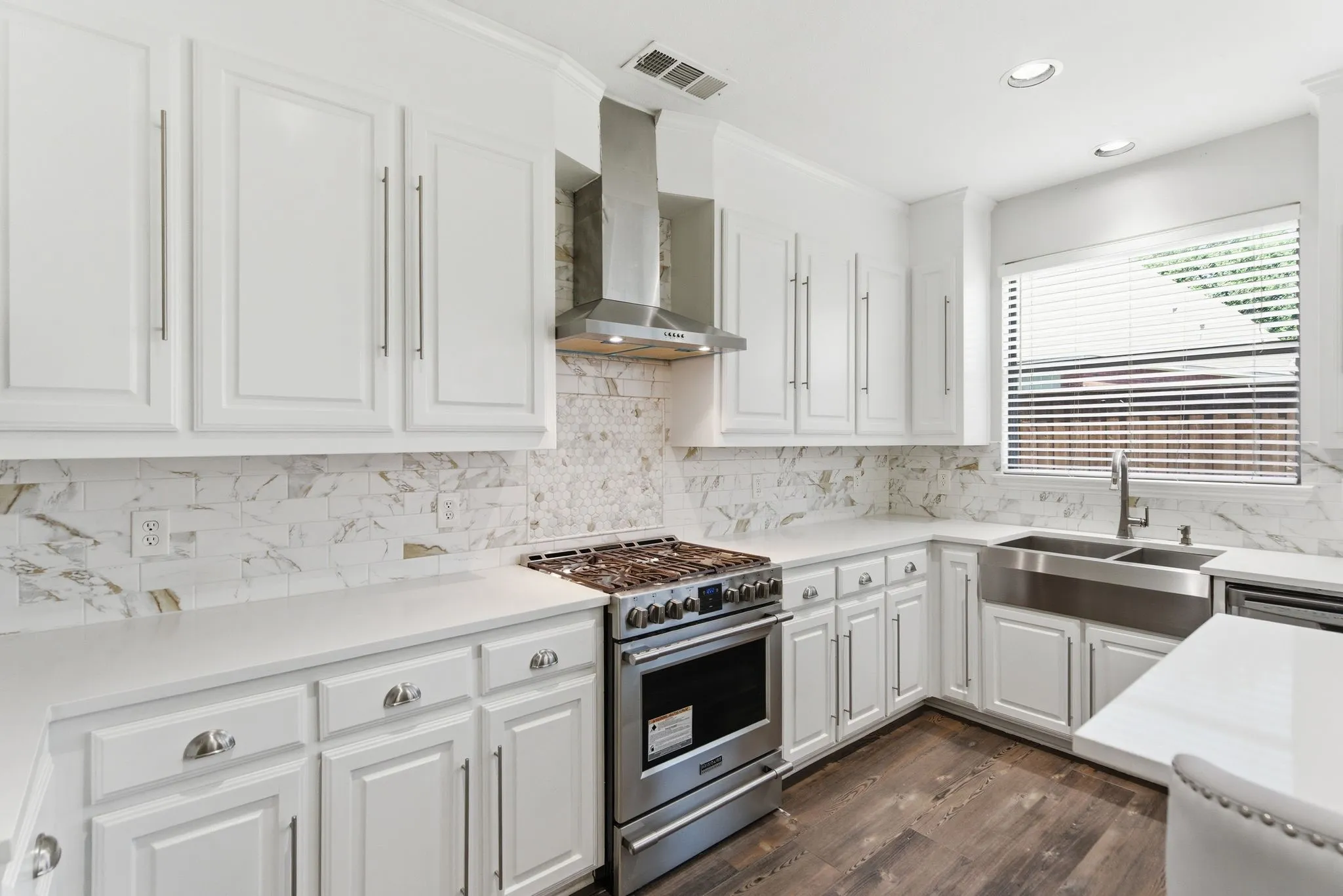 White cabinetry, stainless steel appliances, and a farmhouse sink