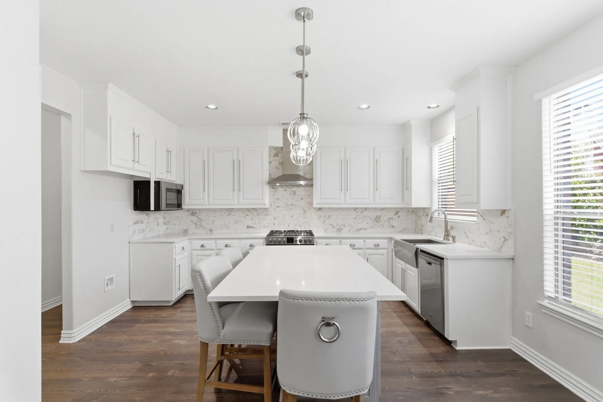 White cabinetry with coordinating countertop, stainless steel appliances, wood-finish flooring, and recessed lighting