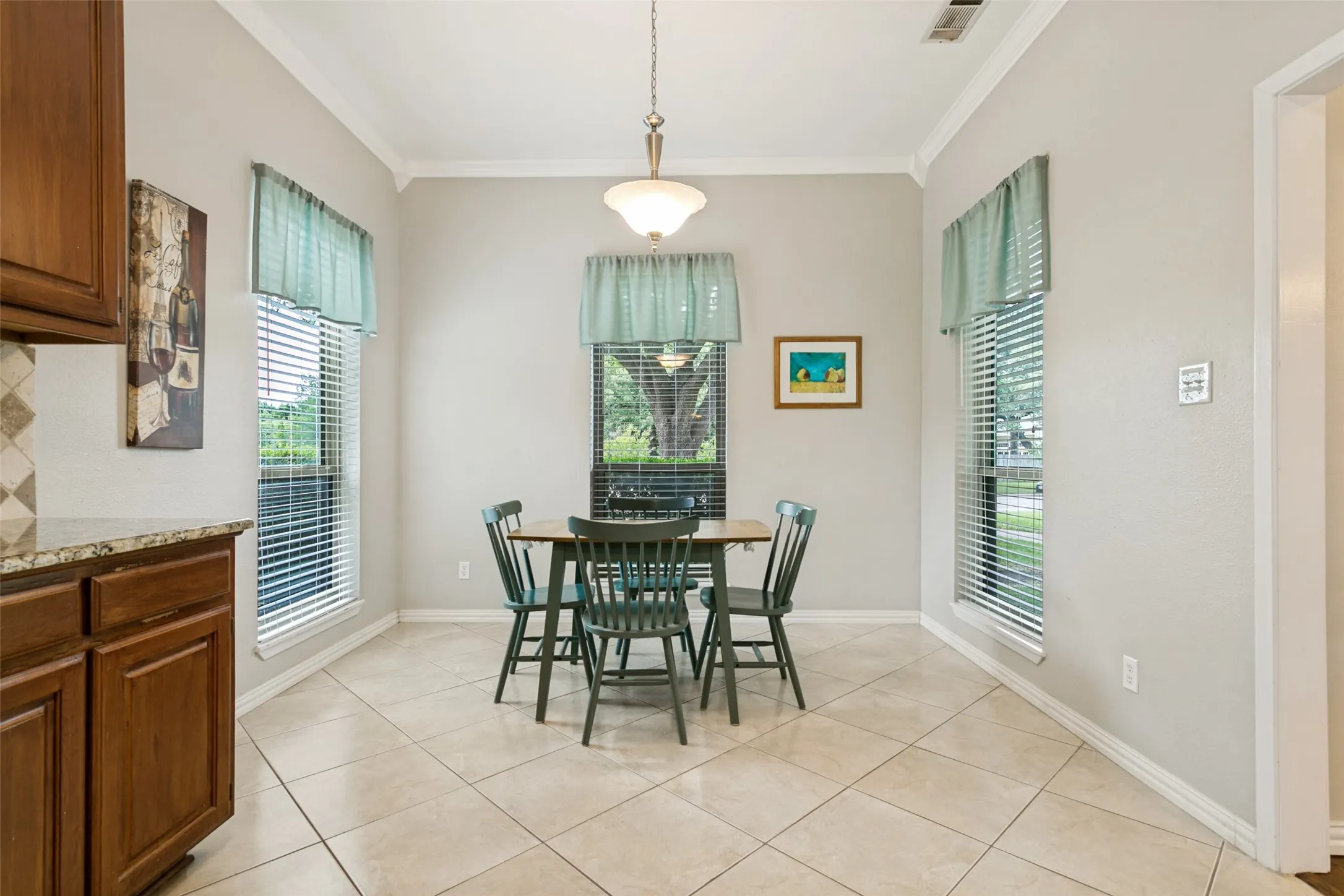 Neutral wall paint, crown molding, tile flooring, recessed windows, and a built-in kitchen cabinet with a patterned backsplash and countertop