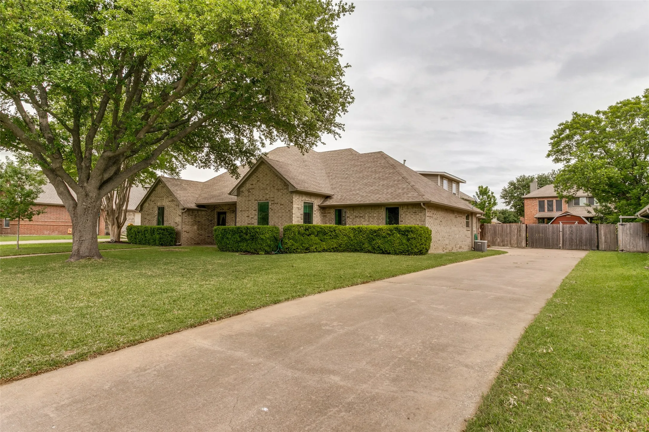 Brick exterior, mature trees, and concrete driveway