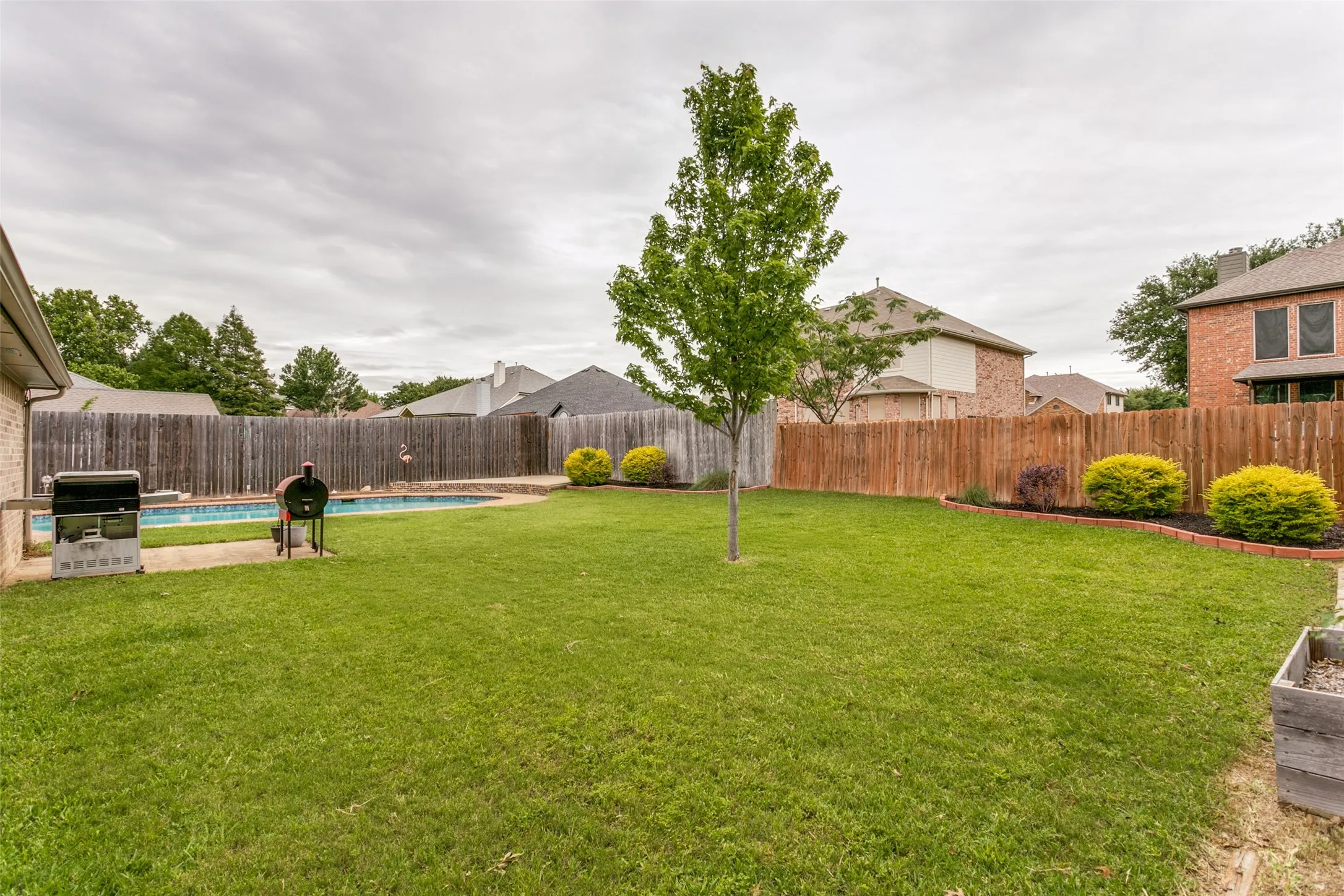 Expansive backyard with a swimming pool, wood privacy fencing, and green lawn
