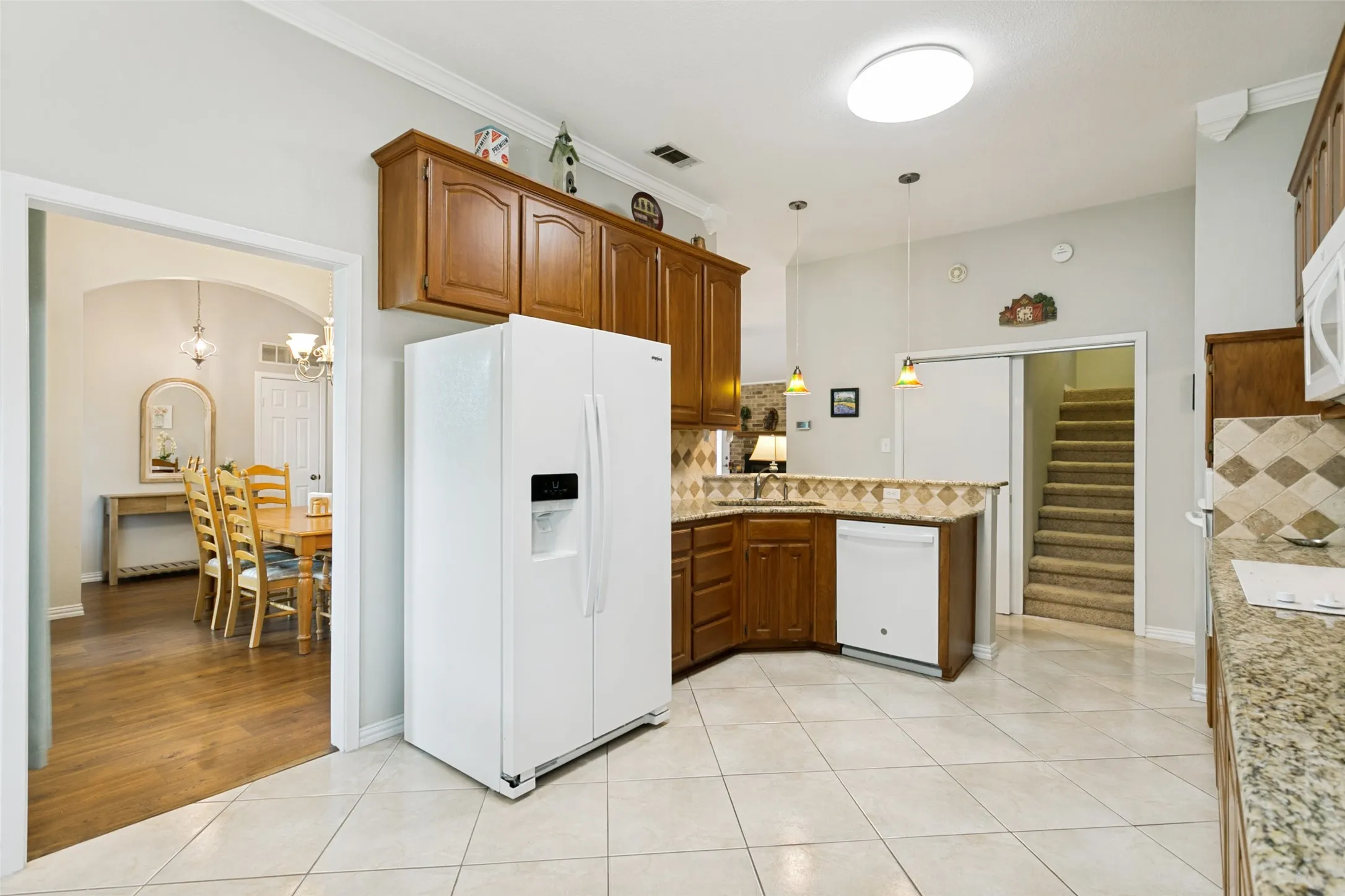 Kitchen featuring tile flooring, wood cabinetry, stone countertops, and a tile backsplash