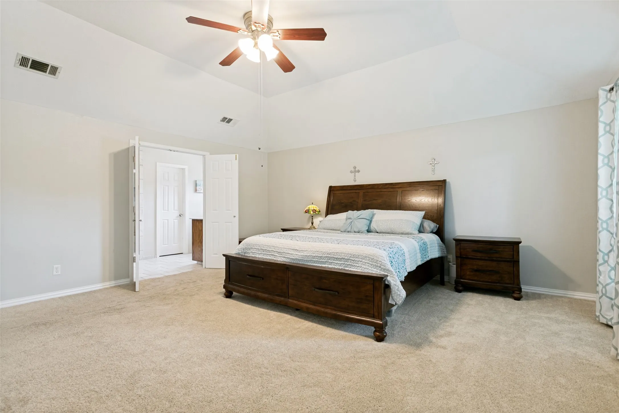 Vaulted ceiling with ceiling fan, light neutral wall color, and carpeted flooring