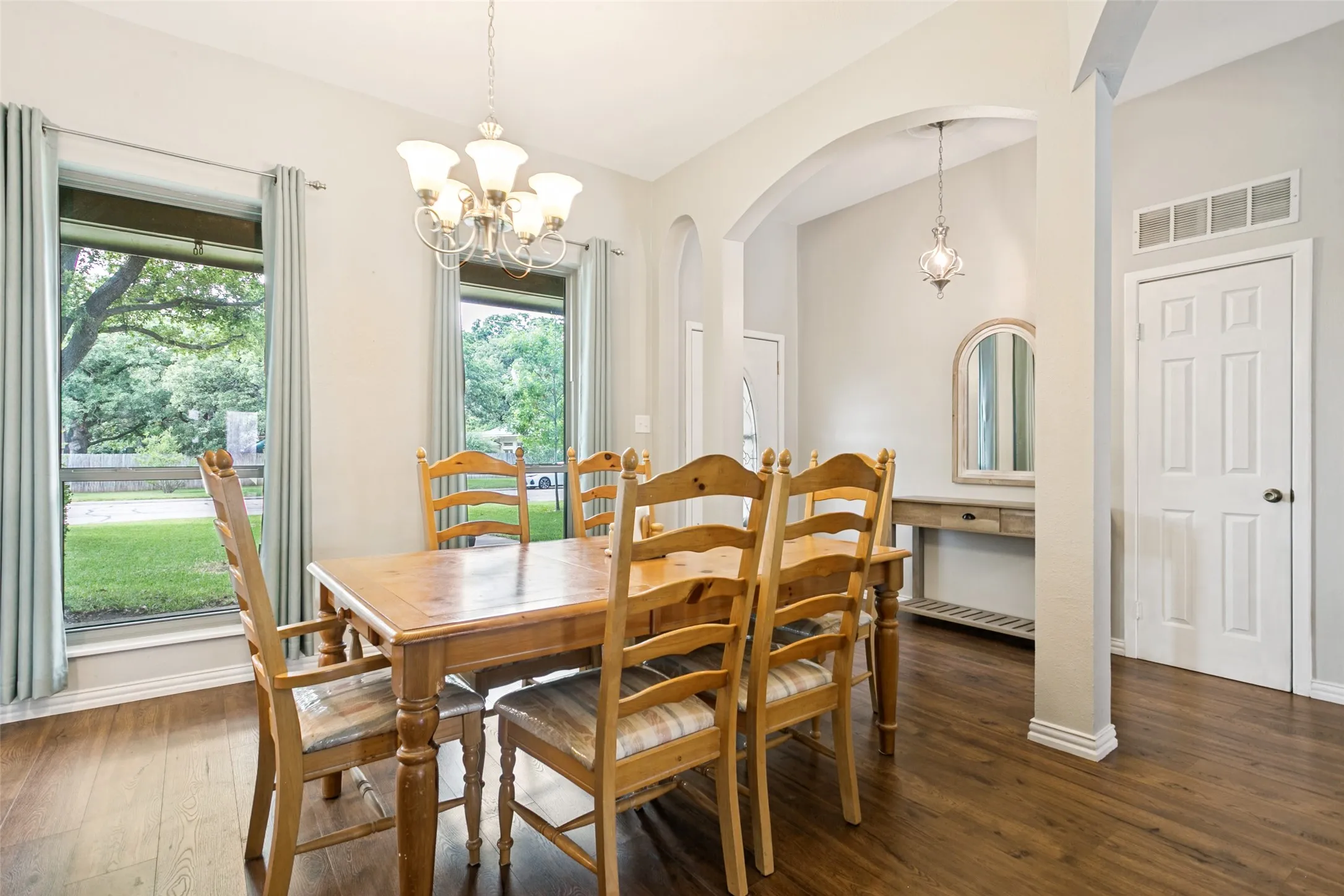 Wood-finish flooring throughout, arched entryway, and a five-light chandelier