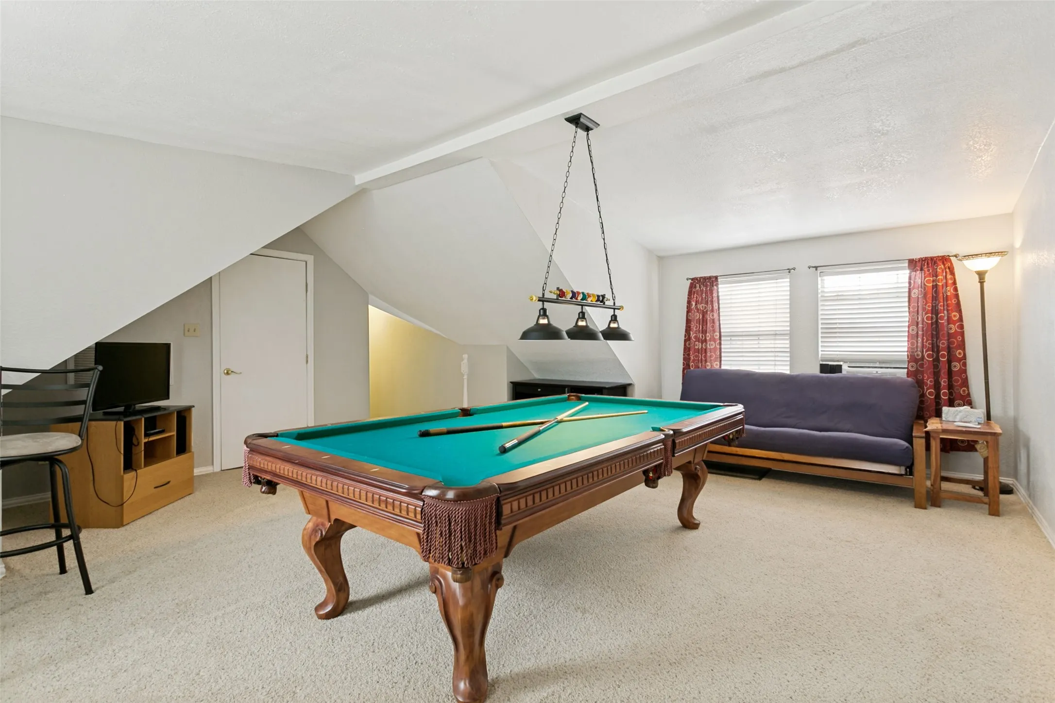 Carpeted room with sloped ceilings, multiple windows, and a built-in light fixture