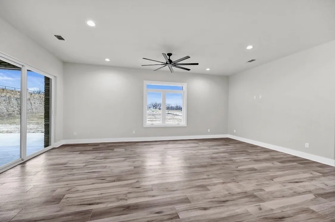 Spacious room featuring wood-finish flooring, recessed lighting, and a contemporary ceiling fan