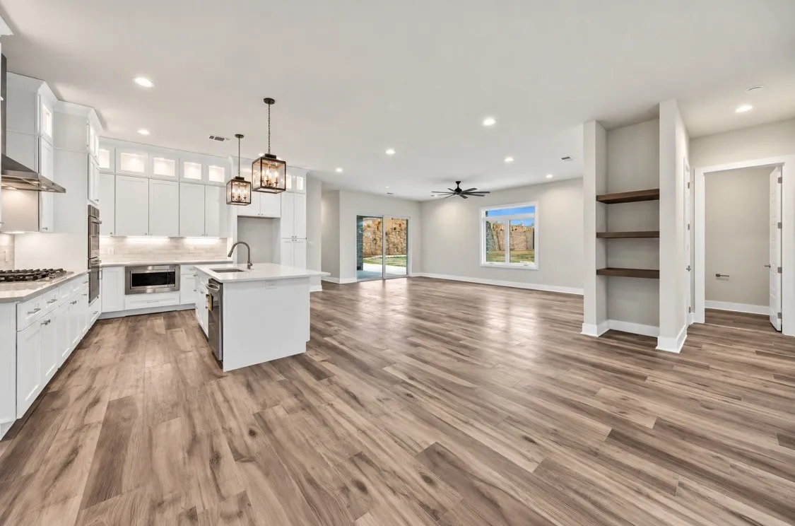 Open-concept living area with wood-finish flooring, recessed lighting, and built-in shelving