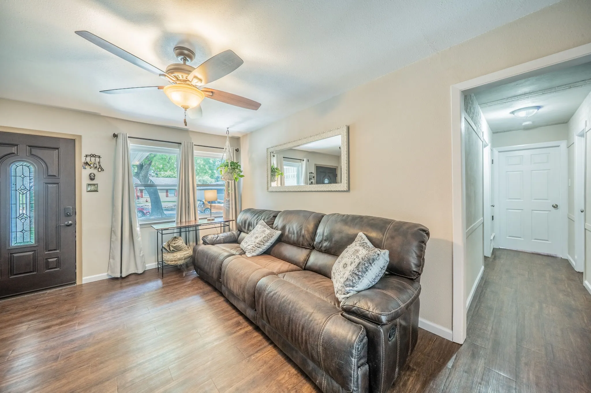  ceiling fan with integrated lighting, multiple windows providing natural light, a hallway with recessed lighting, and a front entry door with decorative glass