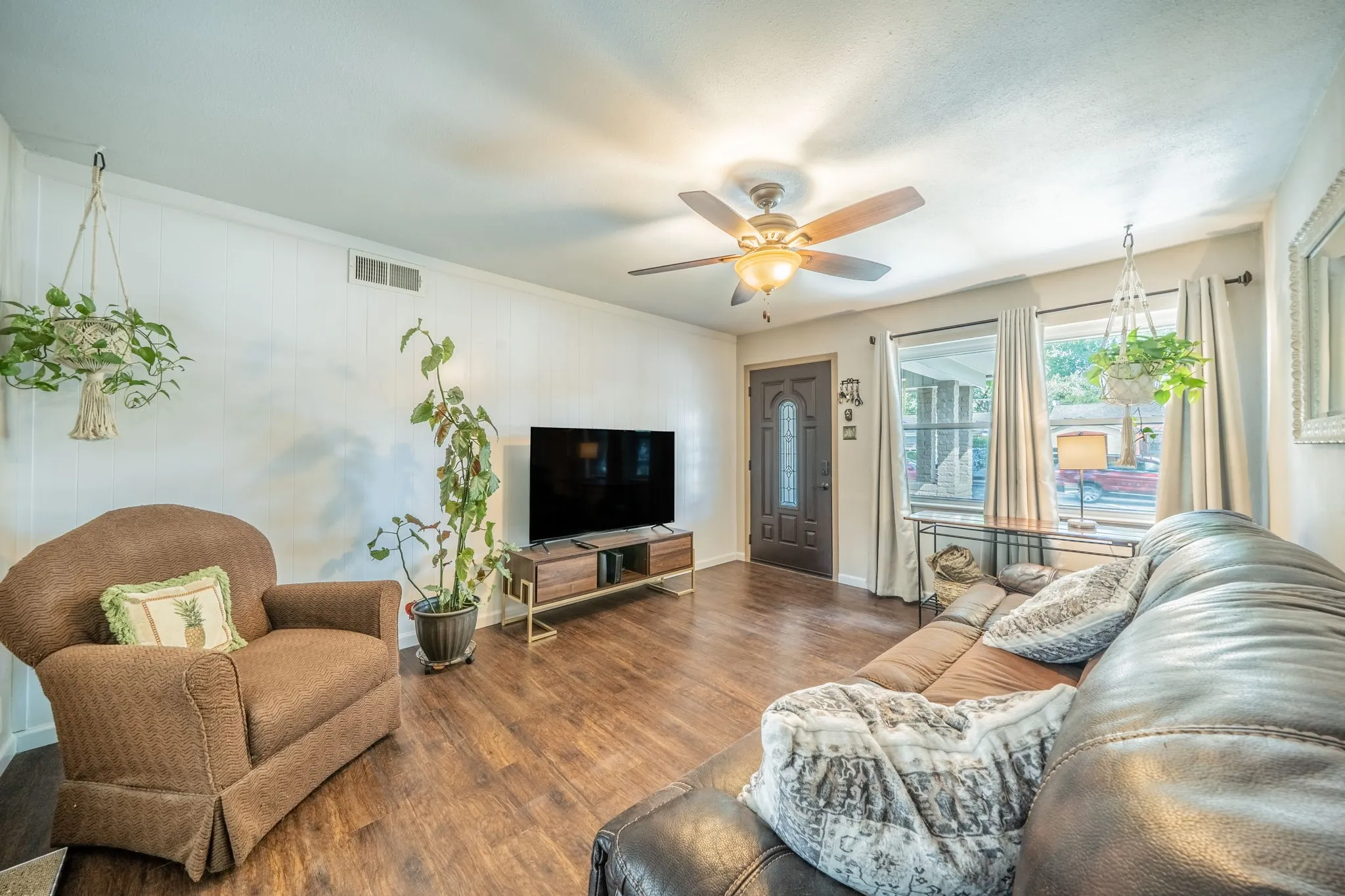 Wood like-finish flooring luxury VPL white paneling, ceiling fan with light fixture, and an entry door with decorative glass paneling