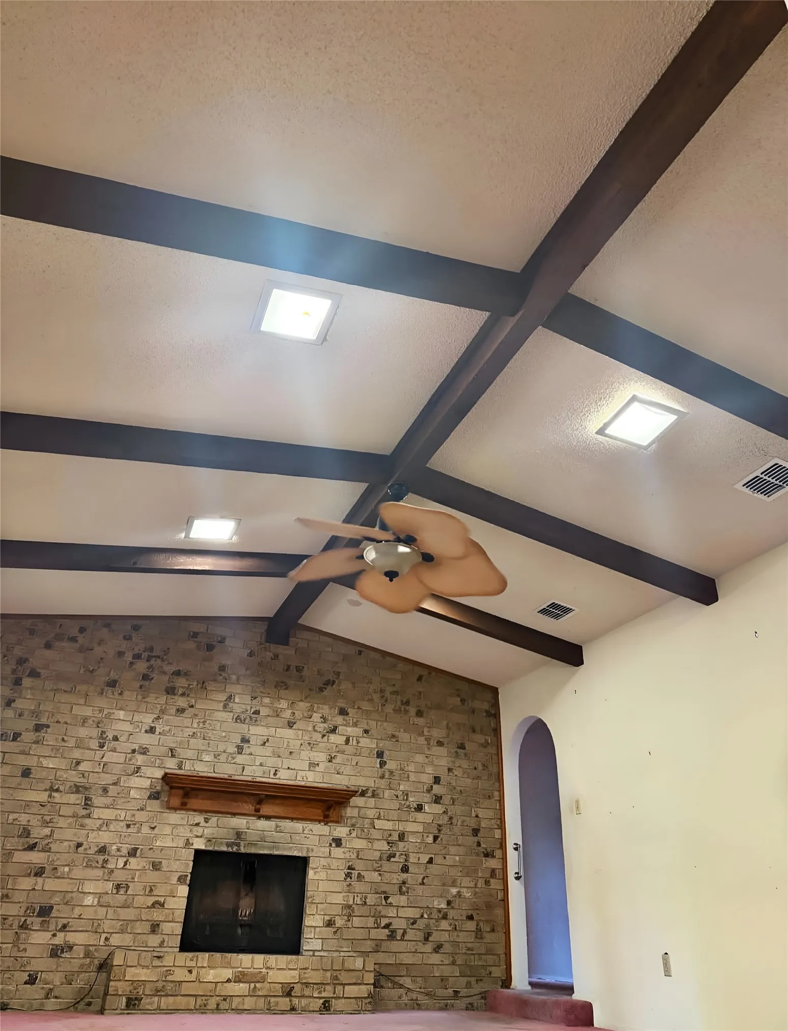 Spacious great room featuring a grand brick fireplace and beautiful vaulted, beamed ceiling.
'