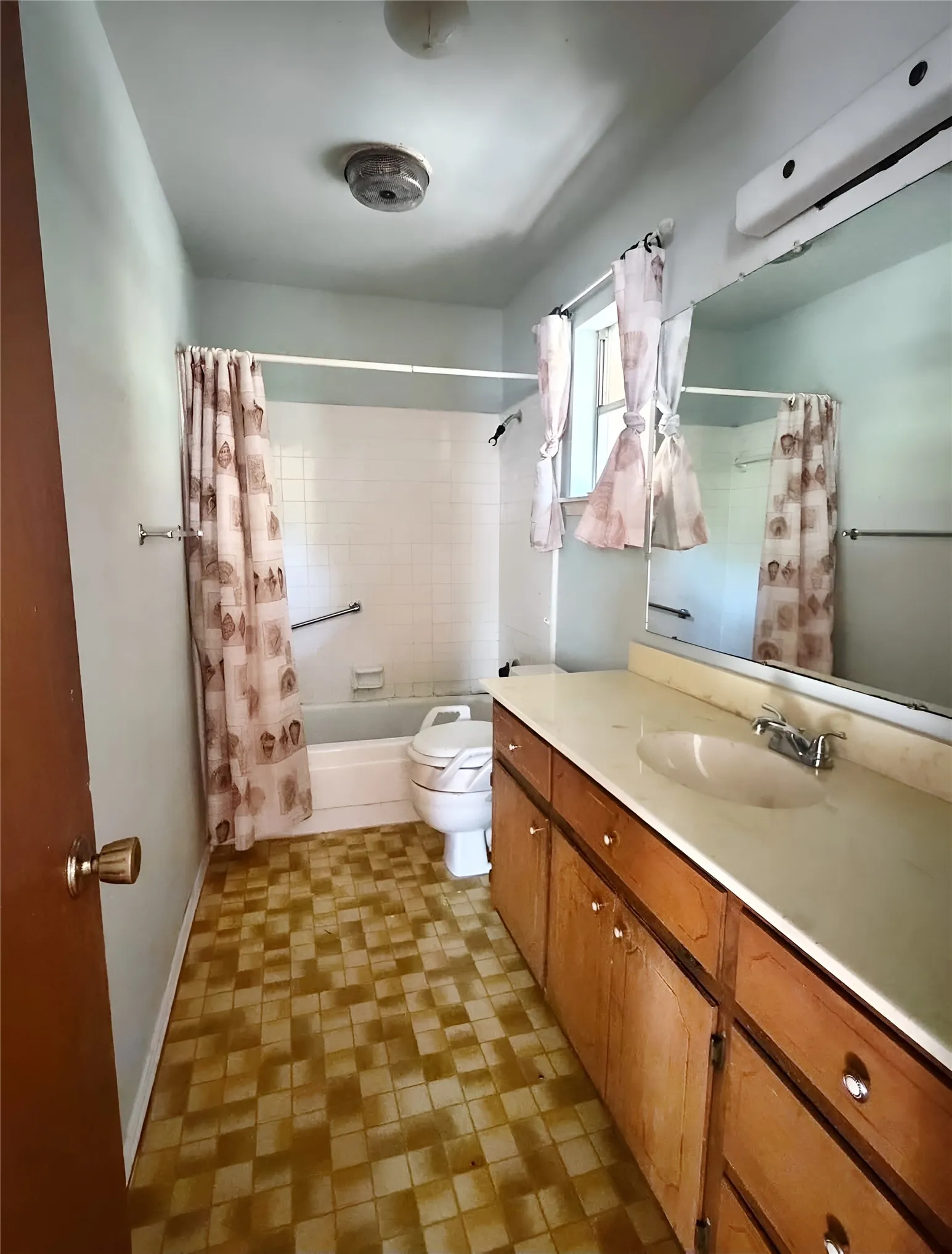Primary bathroom with an extended vanity and ample counter space, wood cabinetry, and natural light.