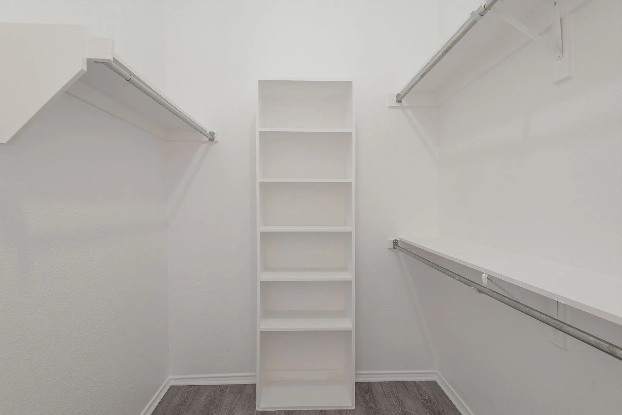 Walk-in closet with built-in shelving, white walls, and wood-finish flooring