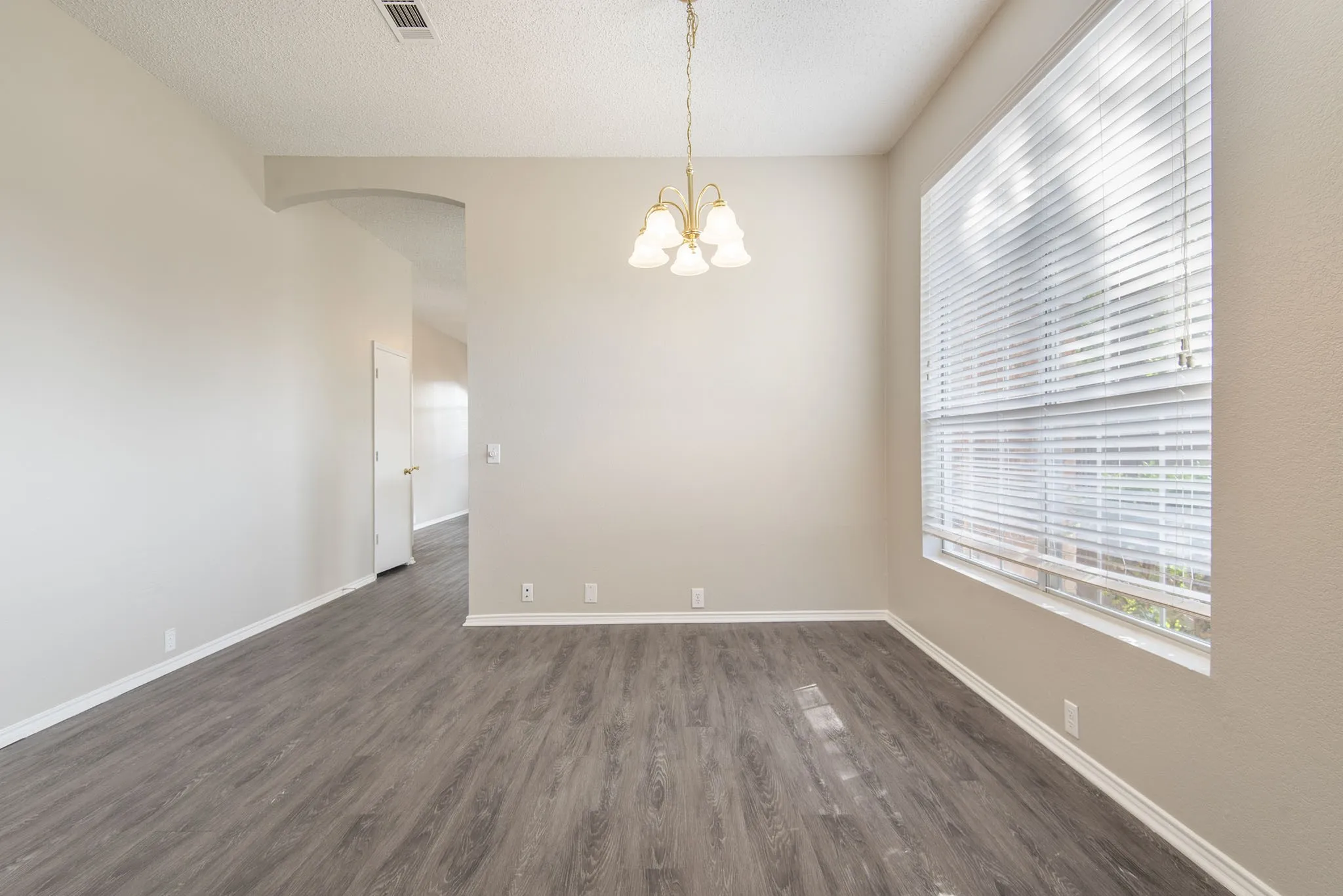 Recessed lighting, wood-finish flooring, and a large window with blinds