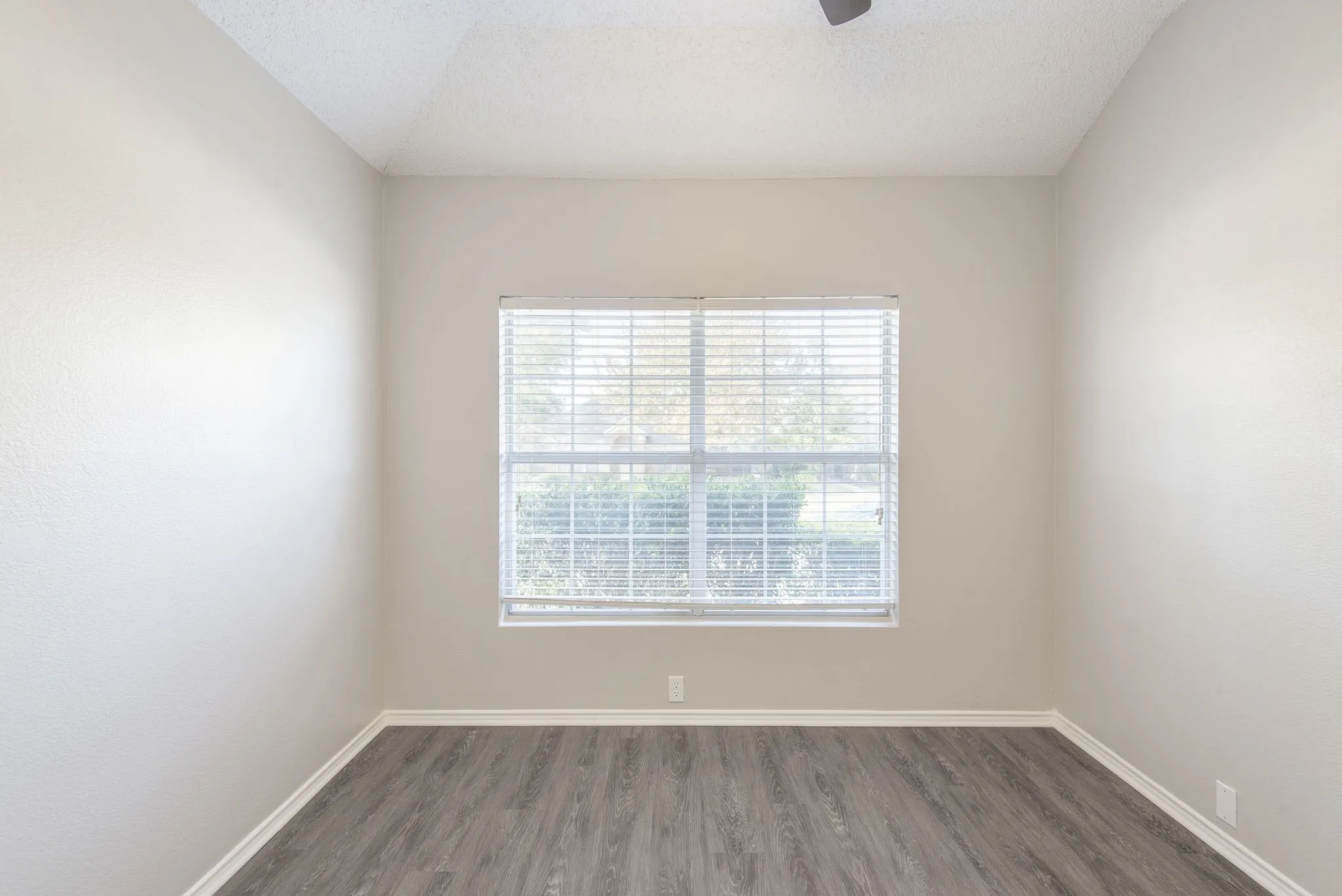 Vaulted ceiling with ceiling fan, wood-finish flooring, and window with blinds