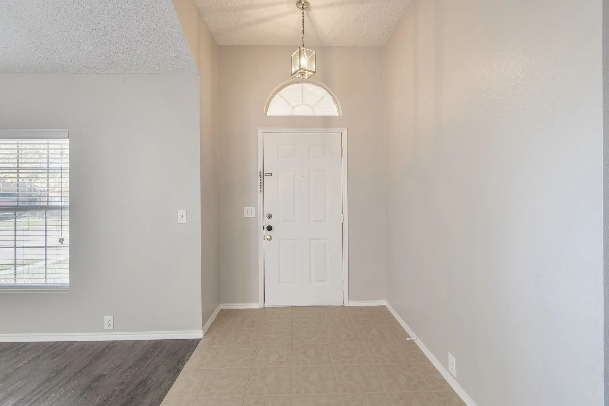 Entryway featuring a decorative transom window, overhead pendant light, and tile flooring