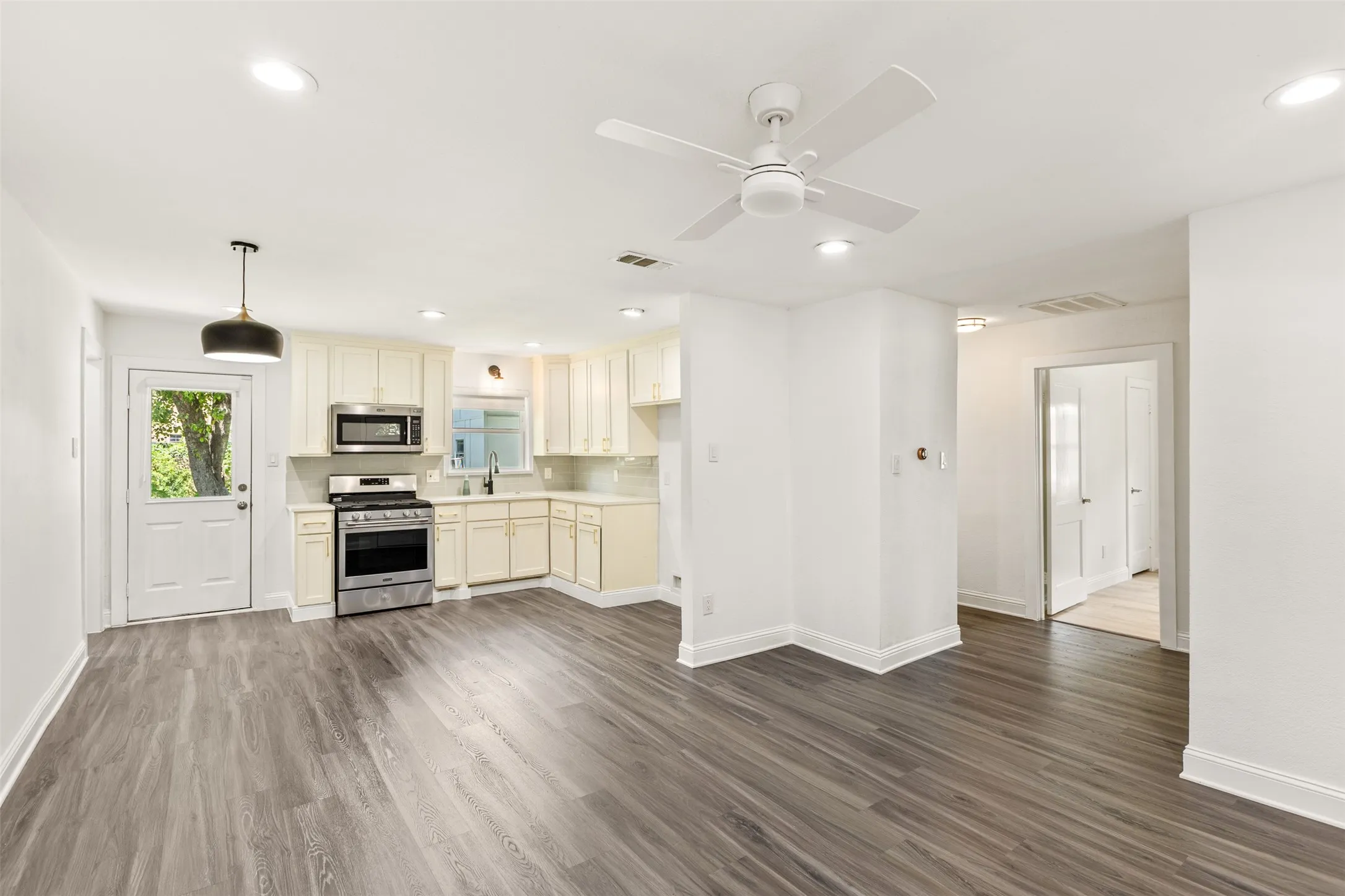 Open-concept living space with wood-finish flooring, recessed lighting, and a ceiling fan