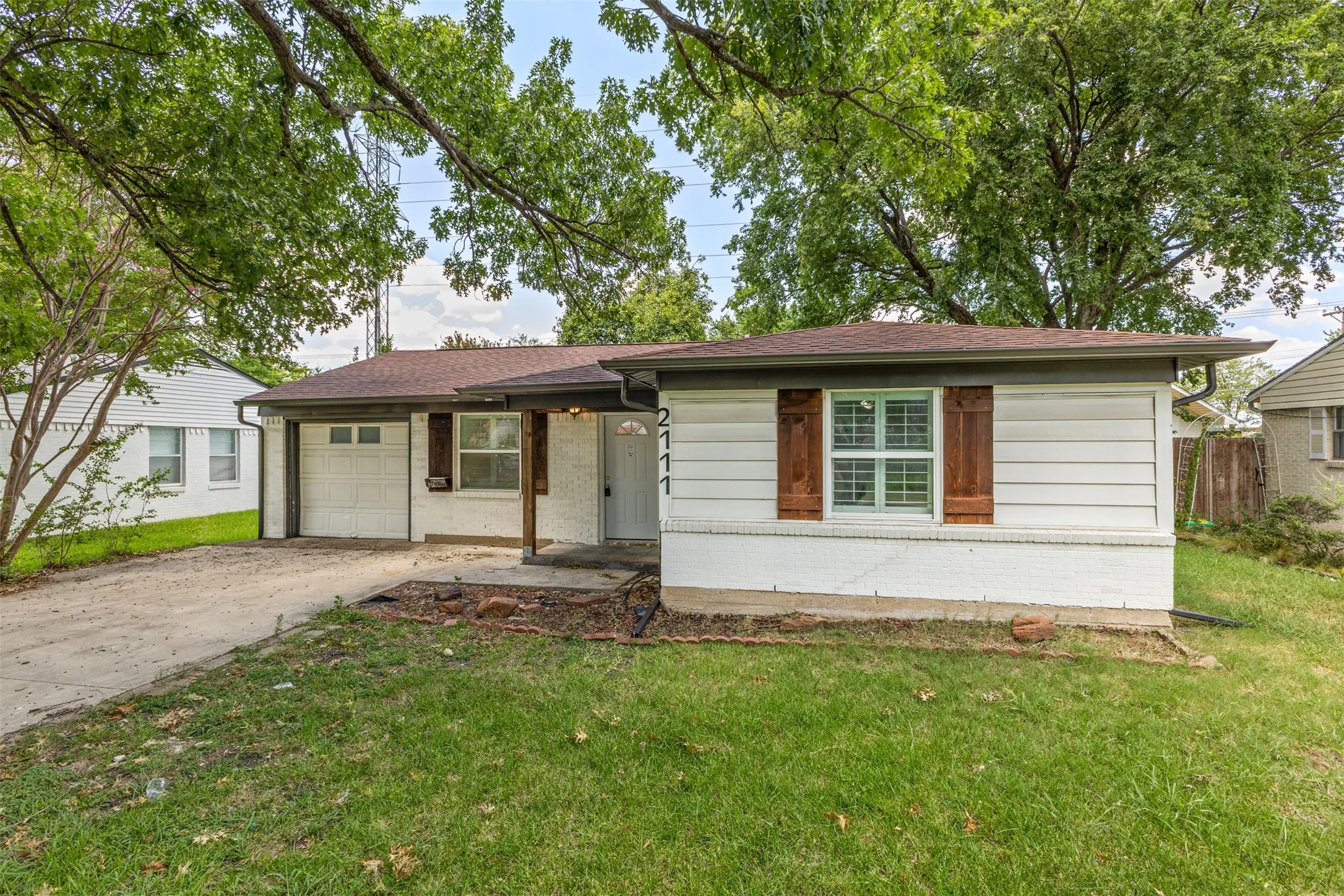 White brick and horizontal siding exterior with a dark brown roof