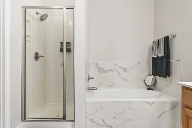 Walk-in shower with clear glass enclosure, a built-in shower caddy, and a polished chrome shower head