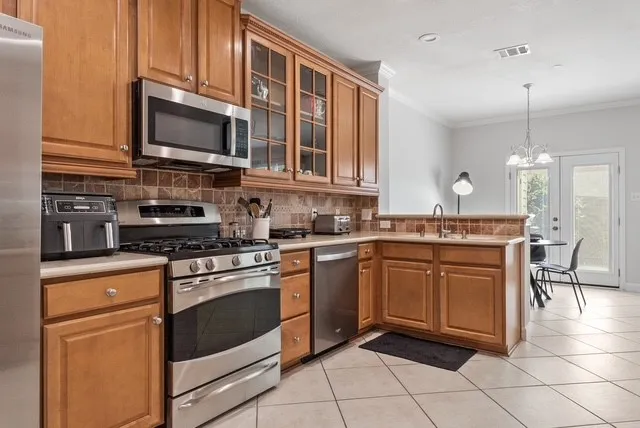 Kitchen featuring wood cabinetry, stainless steel appliances, tile flooring, and a tile backsplash